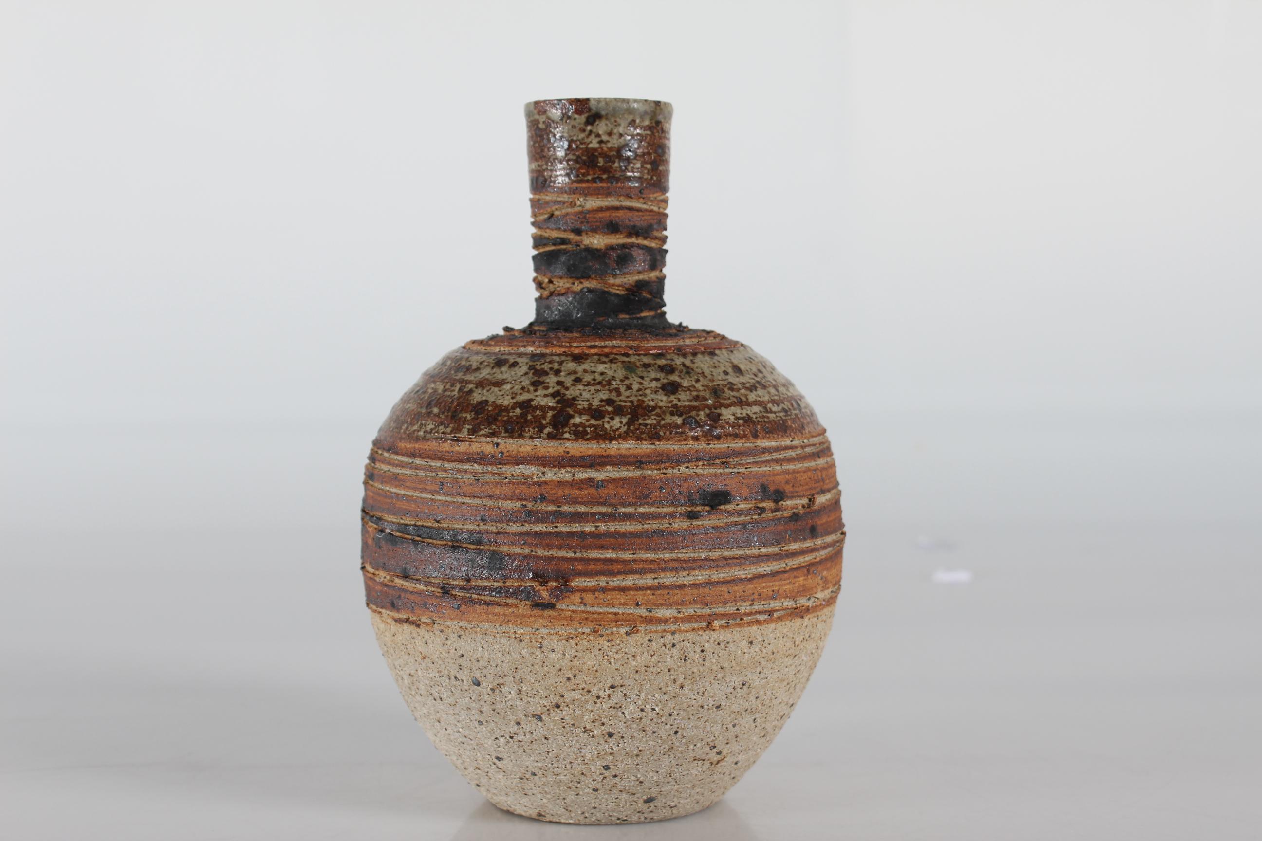 Ceramic vase by Danish ceramist Tue Poulsen (born 1939) from his own studio. Made ca 1970s. 
It is made with chamotte clay and has a rustic expression with incised stripes in earthen colors.

The vase is stamped on bottom: Tue Denmark

Very good