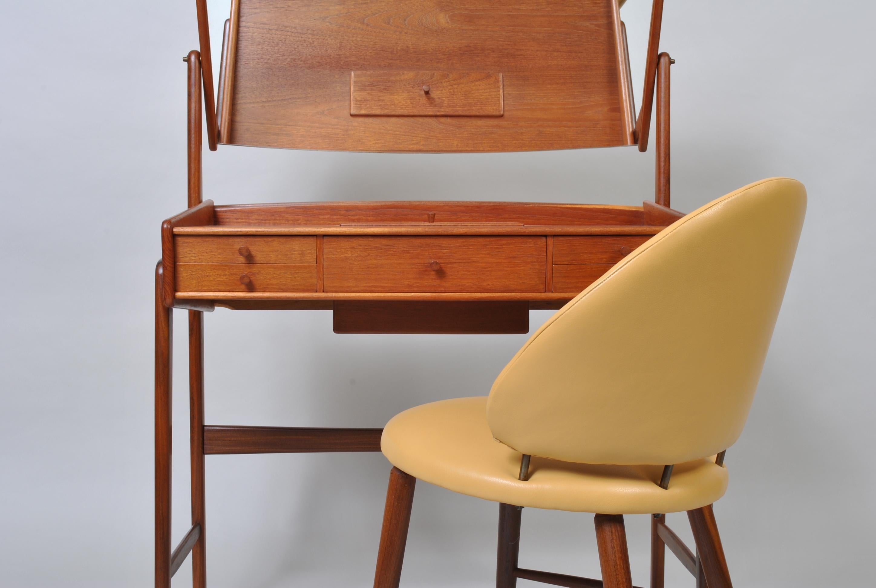 An unusual Danish midcentury vanity table & matching chair by Svend Aage Madsen. The vanity or dressing table is constructed from teak with various small drawers and a lidded compartment within the surface. The original chair has been fully