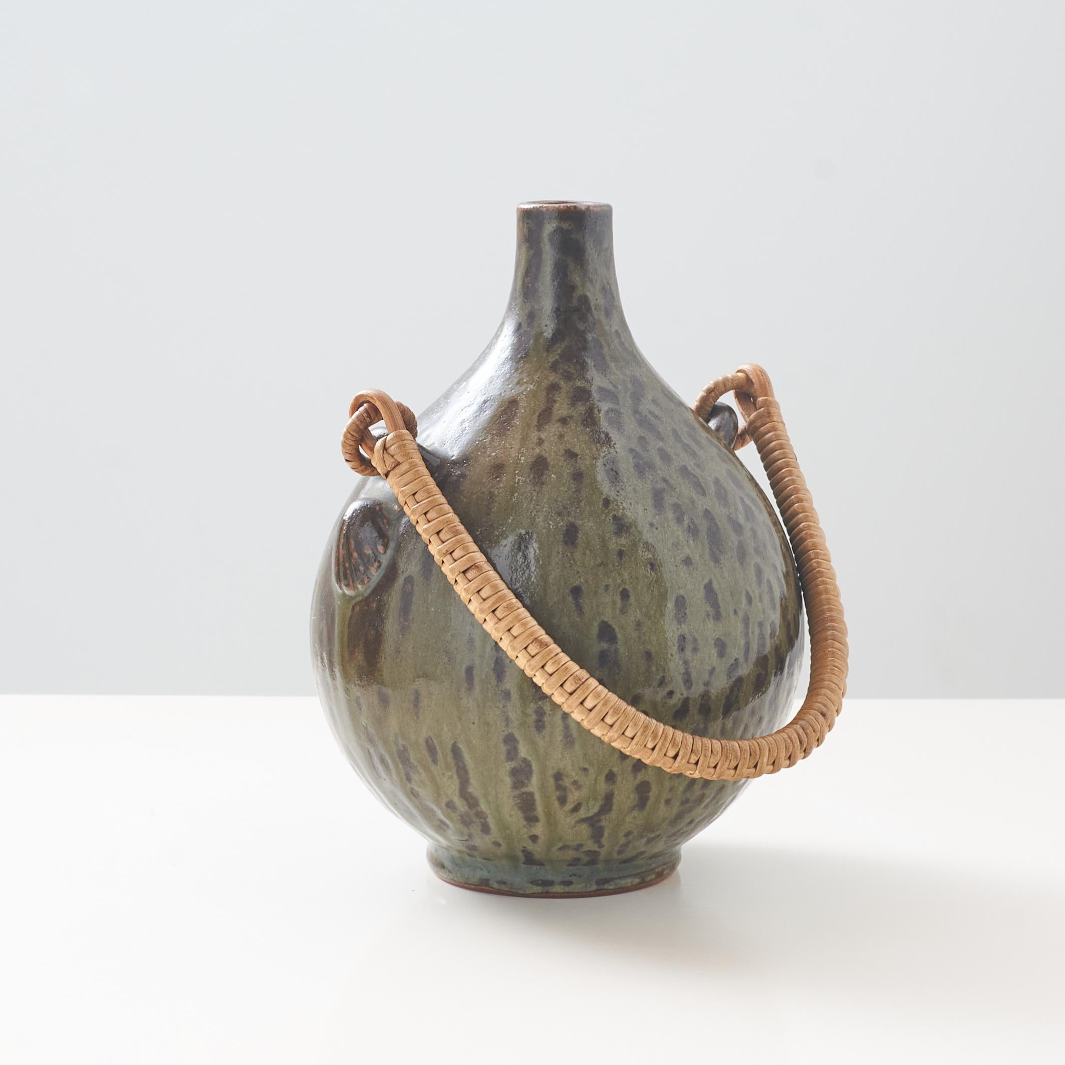 A stylized water pitcher of stoneware with wrapped rattan handle. Marked on base.