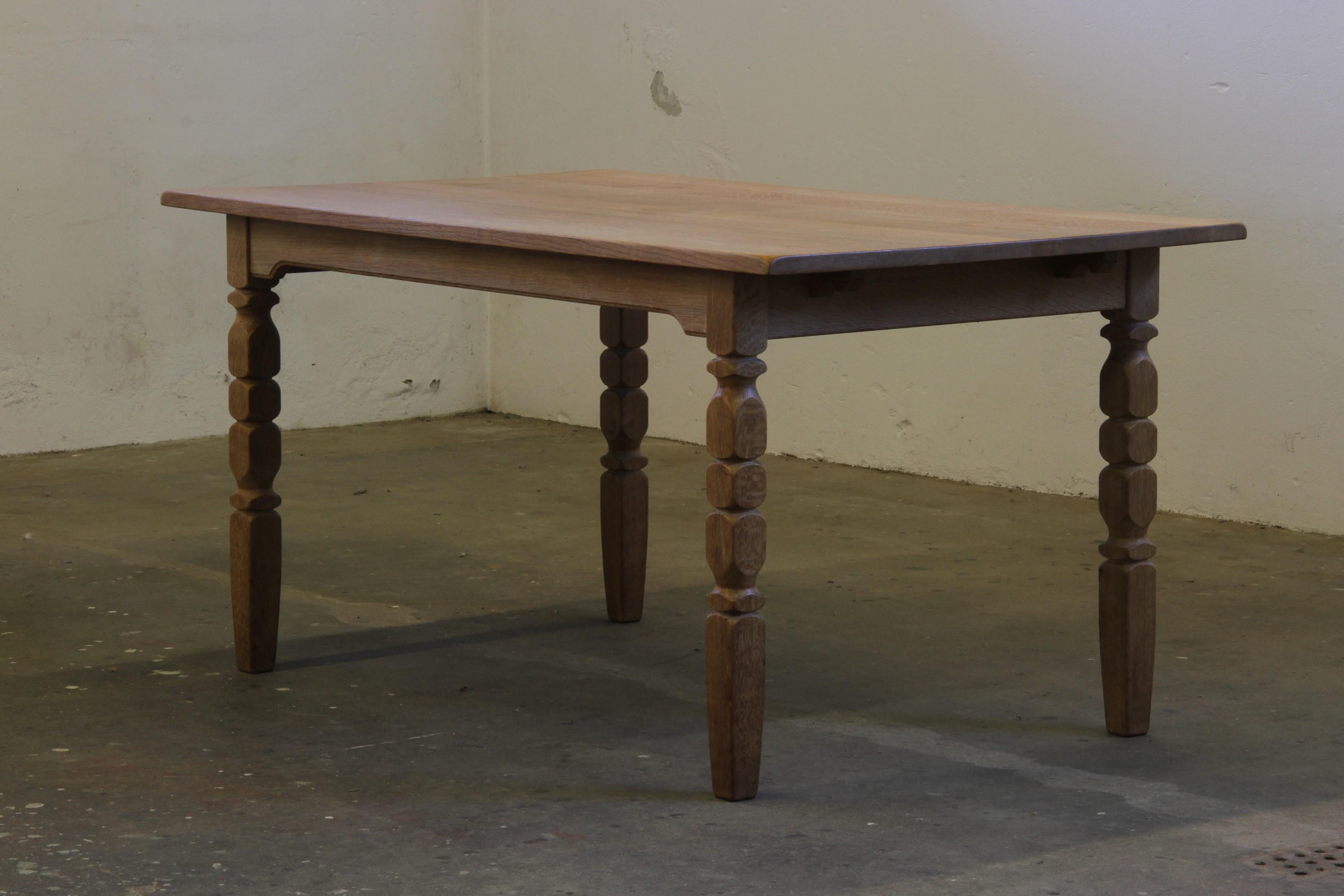 This vintage mid-century oak dining room, or kitchen, table captures the essence of Henning Kjærnulf's design philosophy, blending a bold brutalist aesthetic with refined danish craftsmanship. The intricate leg carvings harmonize beautifully with