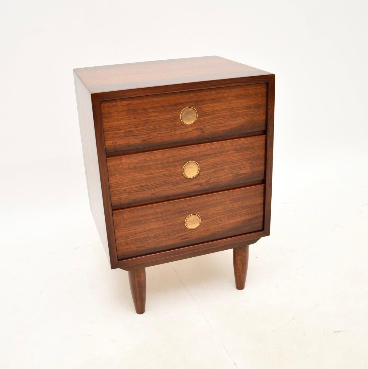 A stylish and extremely well made Danish vintage bedside chest. This was made by Dyrlund, it dates from around the 1960’s.

The quality is outstanding, this sits on tapered legs and has lovely brass circular handles. The grain patterns and colour