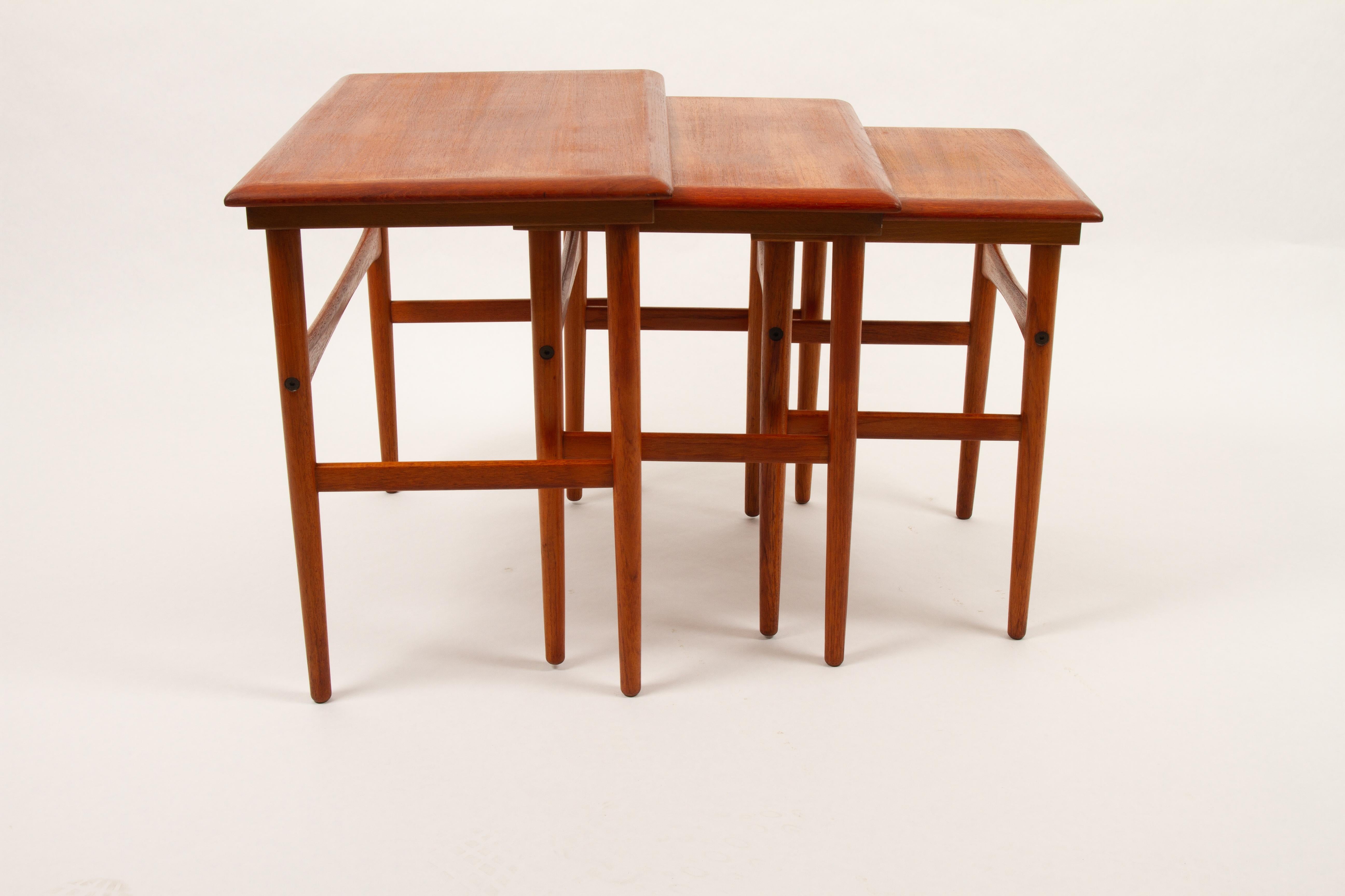 Set of elegant Danish nesting tables. Thin round tapered legs and shaped crossbars. Wide slanting edge in solid teak. Very versatile, can be used together or as individual tables for lamps, plants or decorative items. A Mid-Century Modern must have.