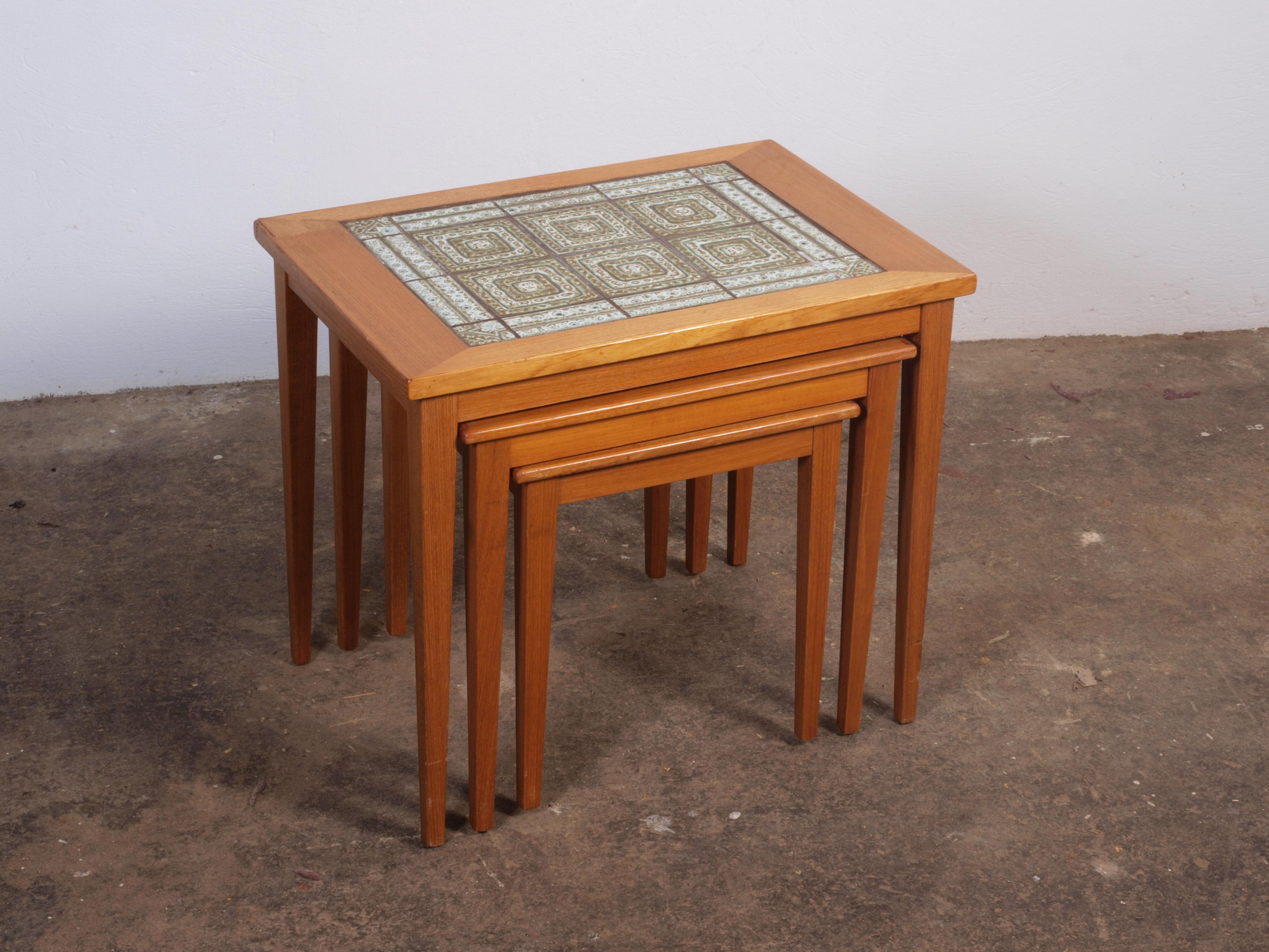 Set of 3 teak nesting tables, Danish mid-century design with the largest table featuring elegant tiles. Despite a minor corner flaw on the big table, they're in beautiful condition. Easily disassembled for affordable air freight. Ideal for modern