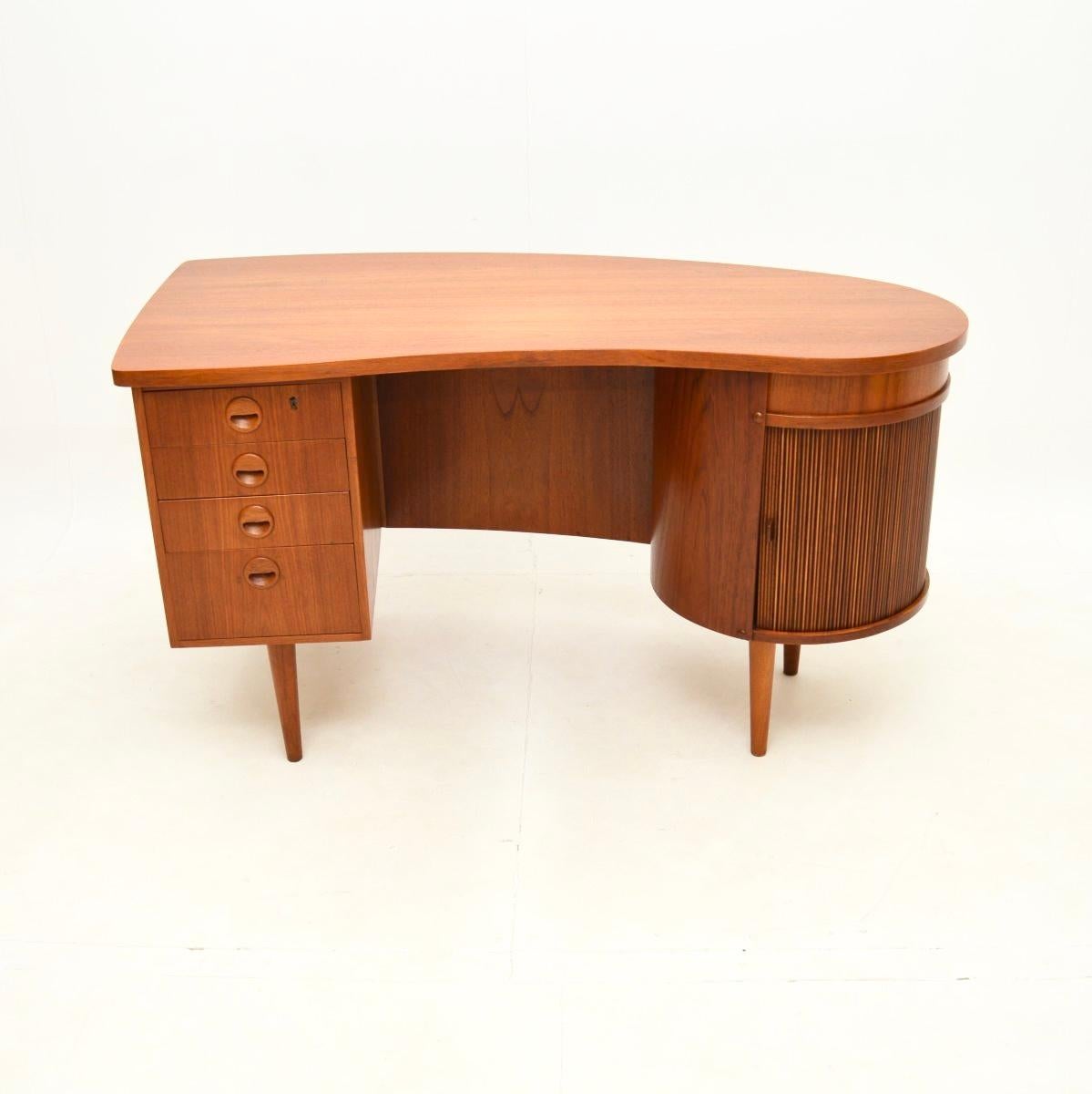 Una scrivania danese vintage in teak assolutamente spettacolare di Kai Kristiansen. Questa è la scrivania modello 54, prodotta in Danimarca negli anni '60.

È di qualità straordinaria e ha un design incredibile. Il piano ha una forma asimmetrica, su