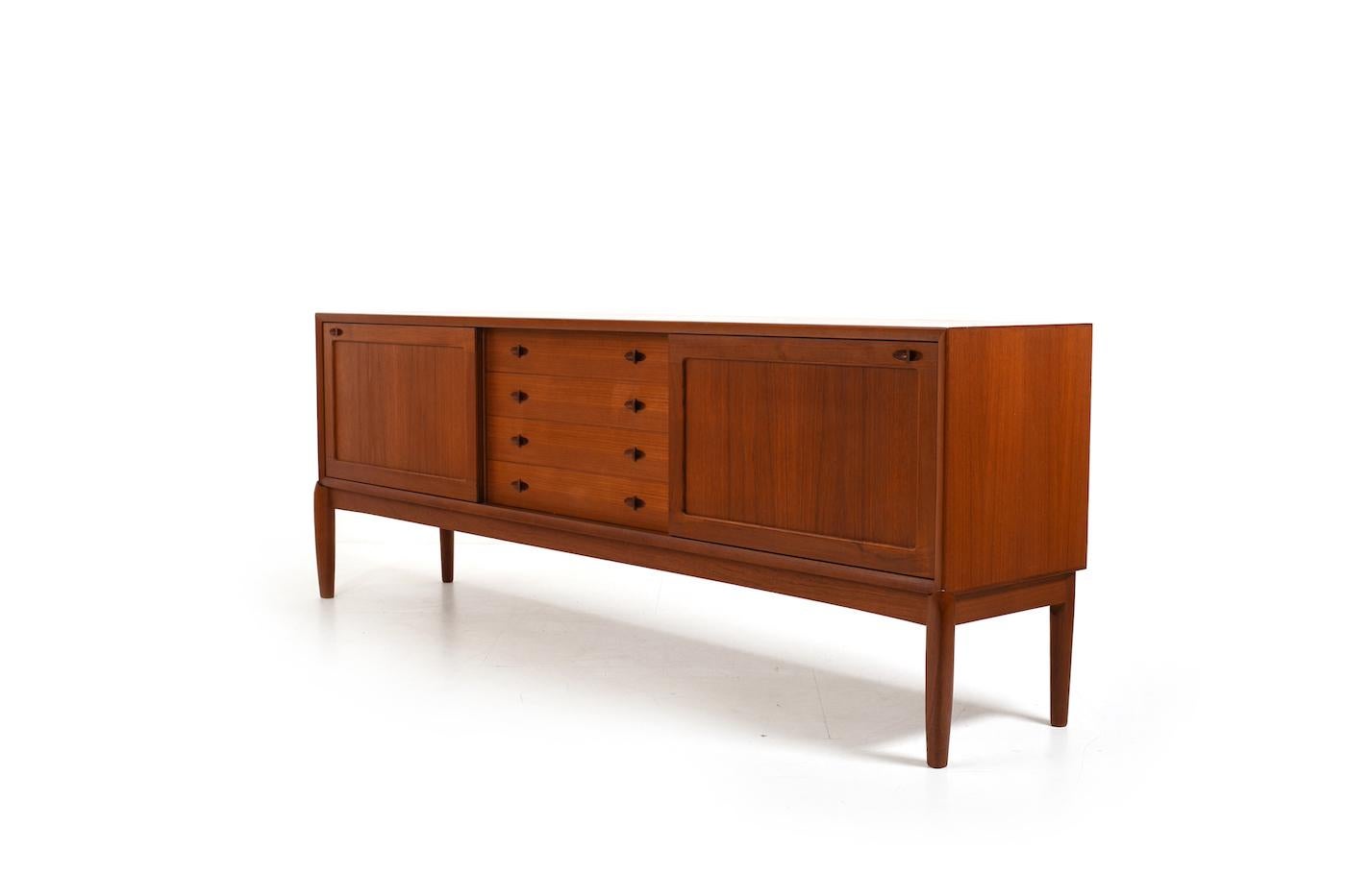  Henry W. Klein teak sideboard. Front with 4 drawers and 2 sliding doors. Behind sliding doors with shelves. Produced by Bramin Denmark 1960s. Beautiful teak color.