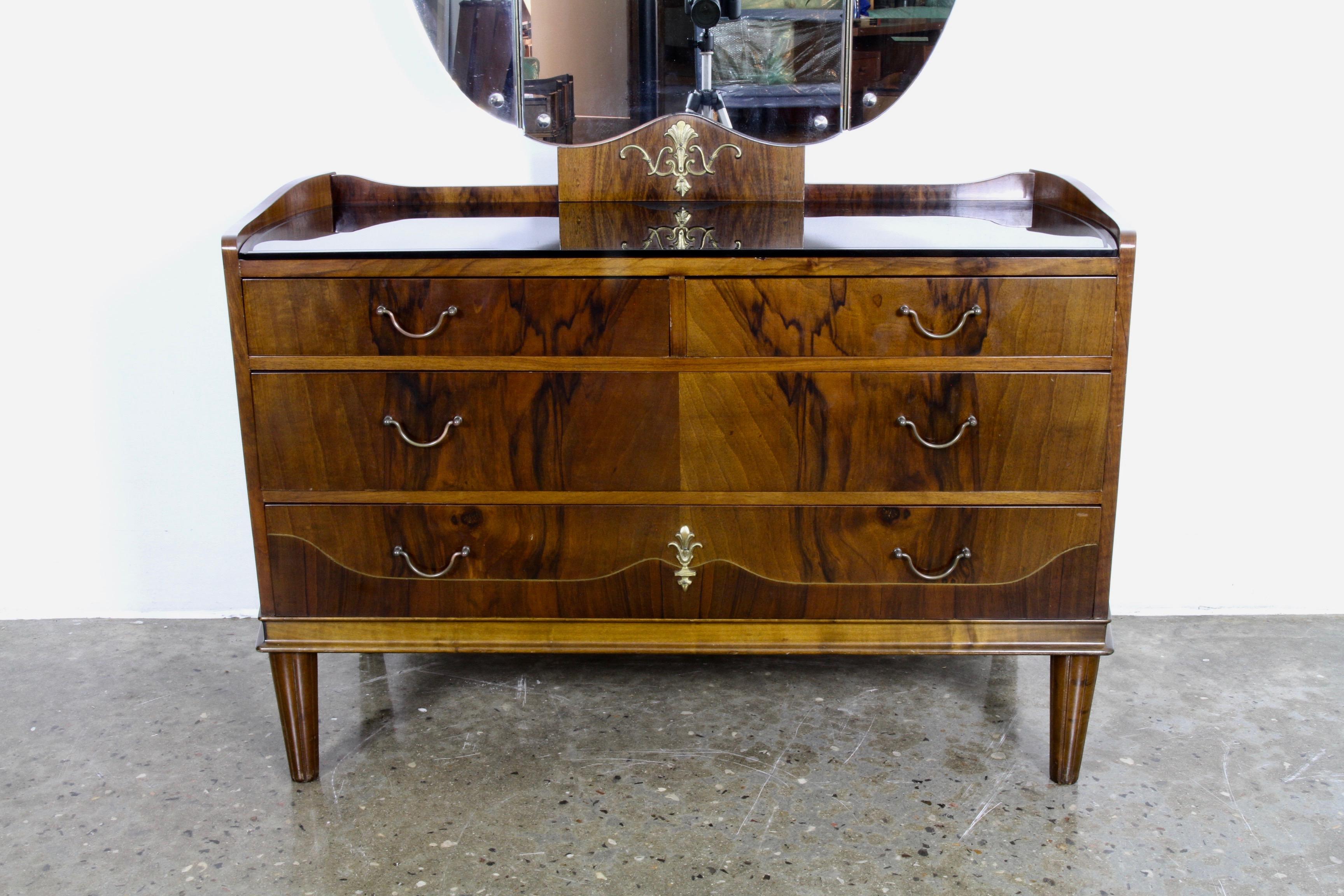 Danish vanity with 2 matching bedside tables. The vanity has a large foldable 3-winged mirror and an elegant black glass top with engraved motifs. 3 large drawers that runs incredibly smooth. Beautiful walnut veneer. Nightstands has matching glass