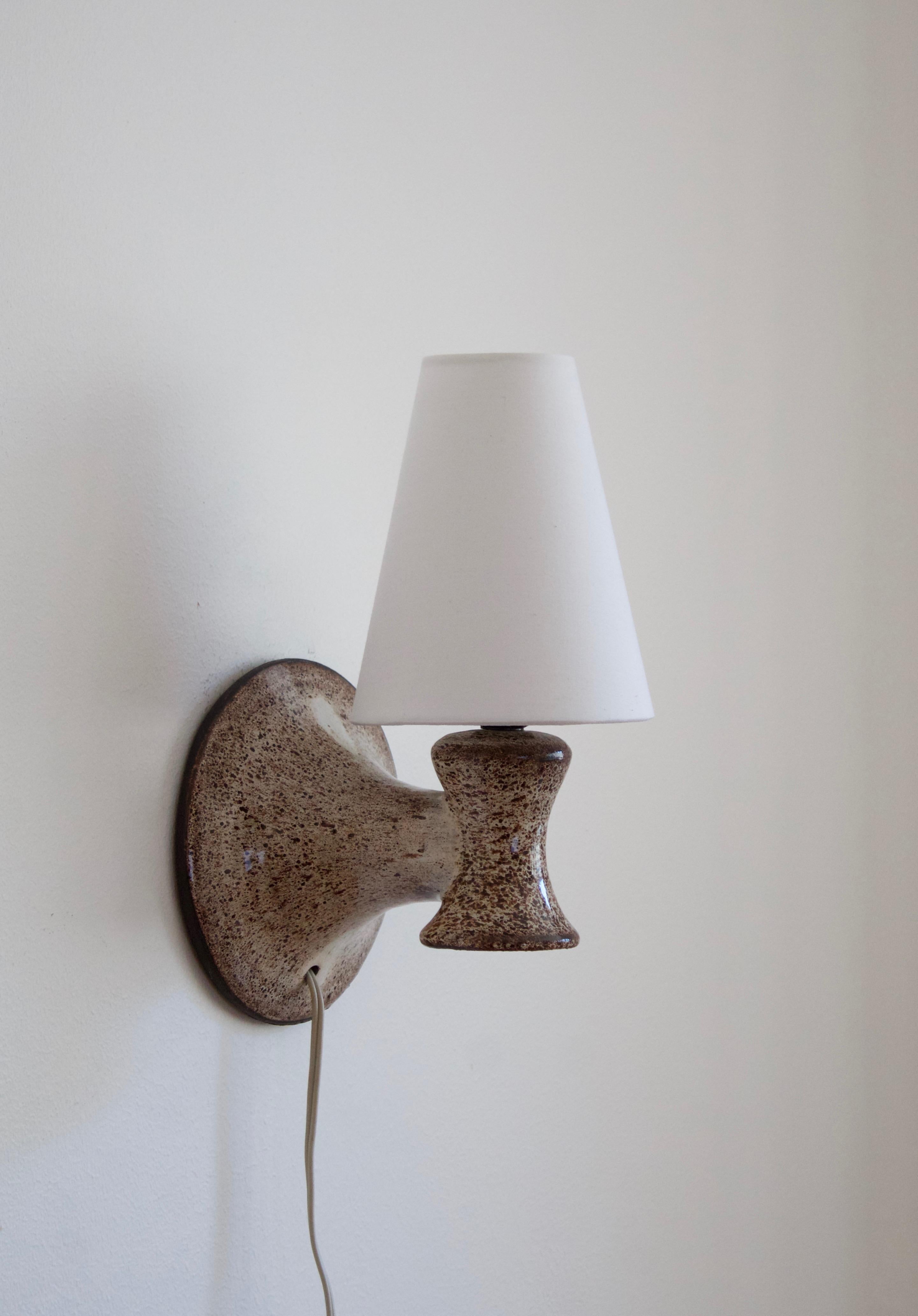A wall light / sconce. Designed and produced in Denmark, c. 1960s. In glazed stoneware. Brand new fabric lampshade.

Stated dimensions include the lampshade attached.