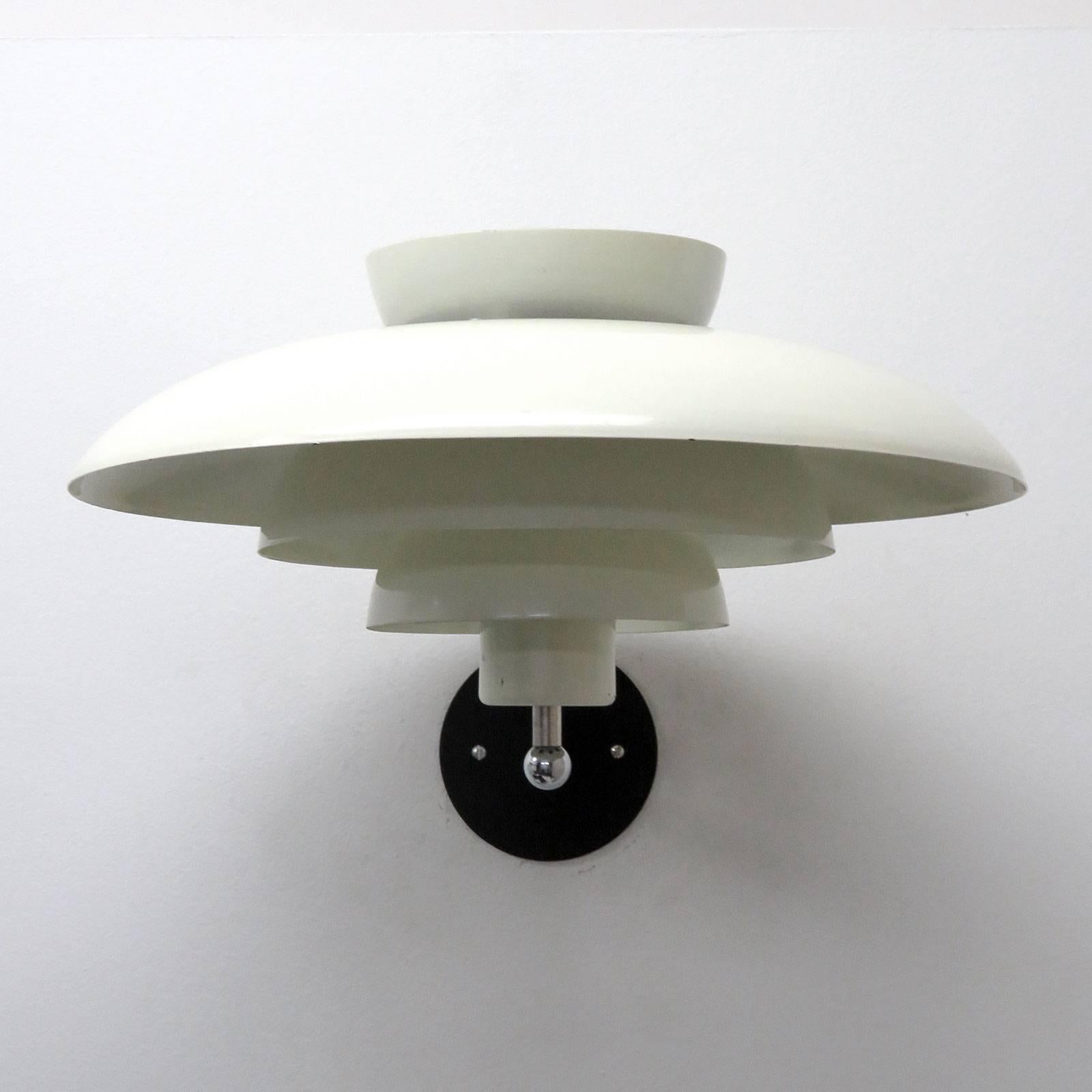 Wonderful tiered Danish wall lights by Horn with white enameled metal rings of different sizes perched on a minimal chrome arm, can be mounted upside down as well, wired for US standards, one E27 socket per fixture, max. wattage 75w, bulbs provided