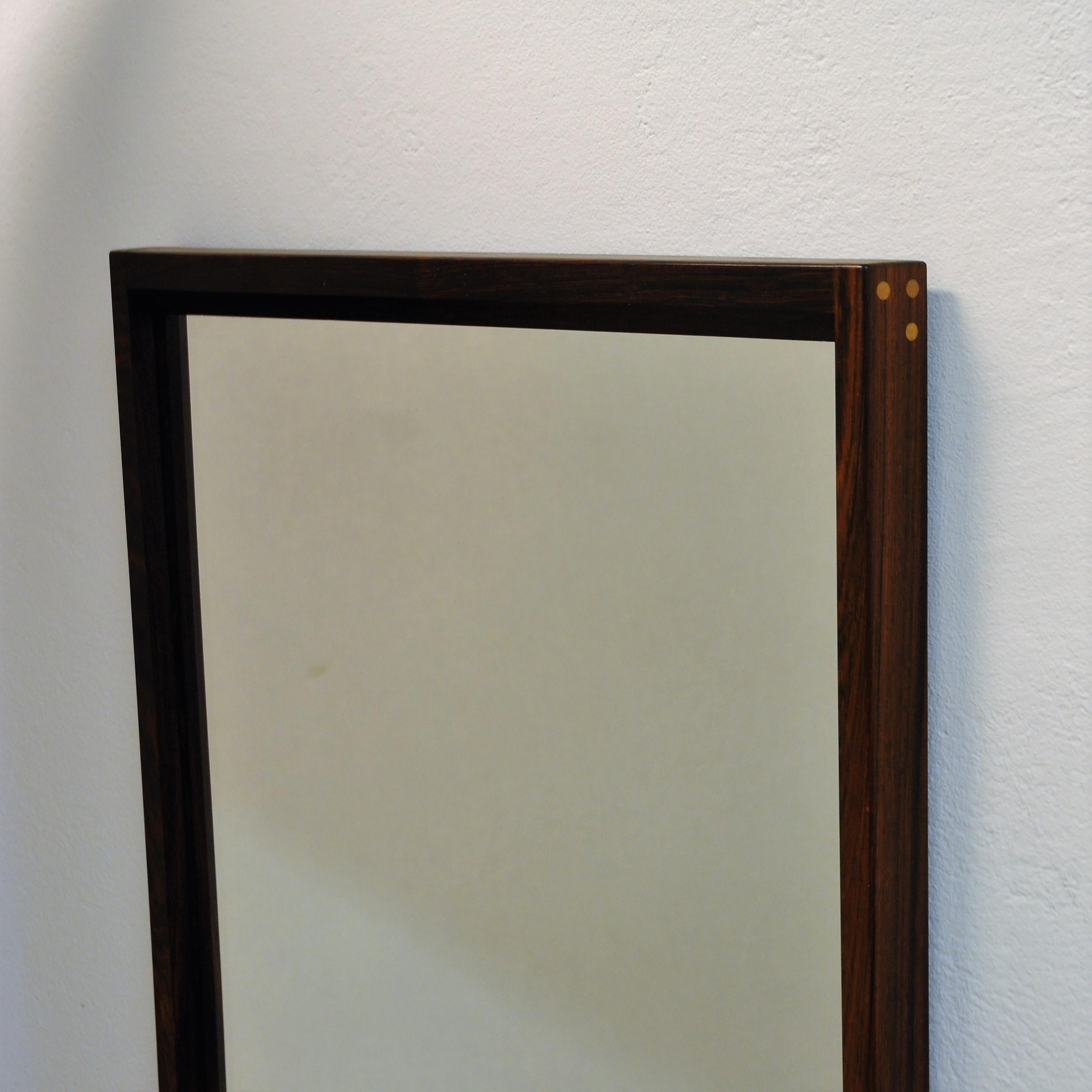 Danish rosewood wall mirror of by Aksel Kjersgaard, Denmark. Marked on the backside with Aksel Kjersgaard and numbered No 145 K. Produced by Odder. This mirror is of a great quality in construction and has beautiful details, such as the visible