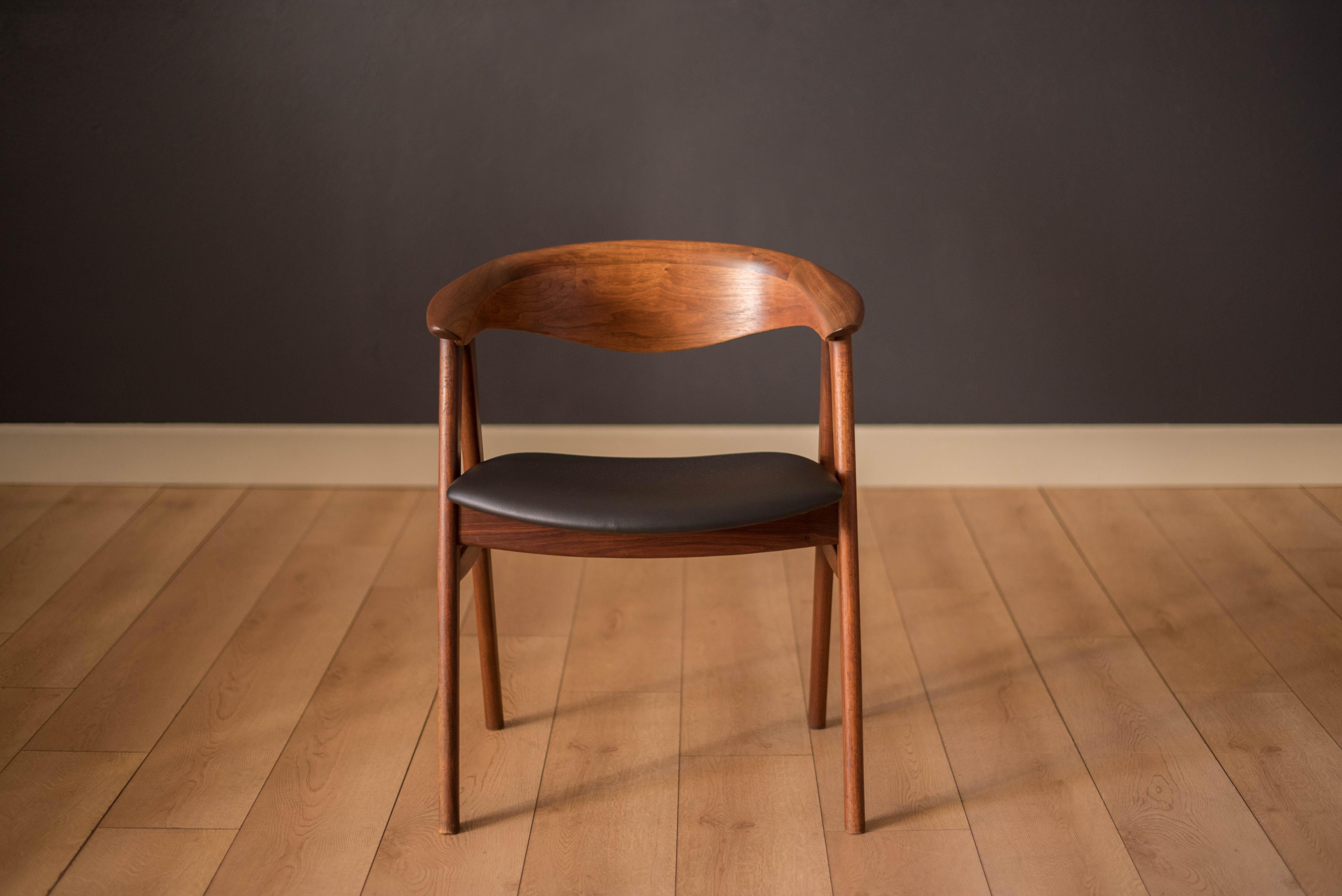 Mid-Century Modern chair in walnut designed by Erik Kirkegaard for Hong Stølefabrik model no. 52 imported by DUX. This side chair features a sculpted backrest and the seat has been newly reupholstered in black vinyl. Perfect to use as a captain