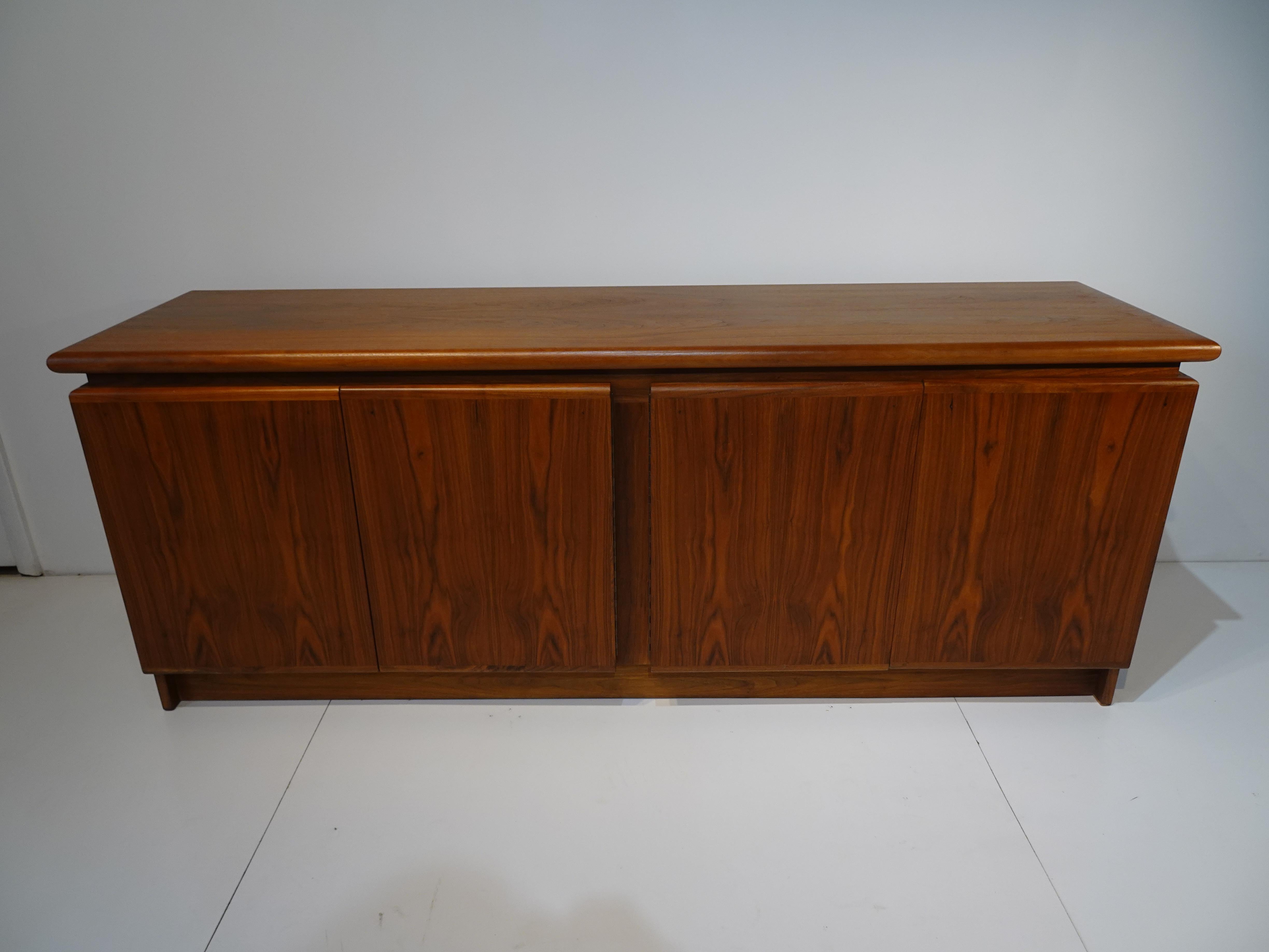 A very well crafted mid century four door walnut credenza or sideboard with adjustable shelves, the top has a floating soft rolled edge giving the piece great lines . The wood has flamed book matched walnut graining to the doors and sides, made in