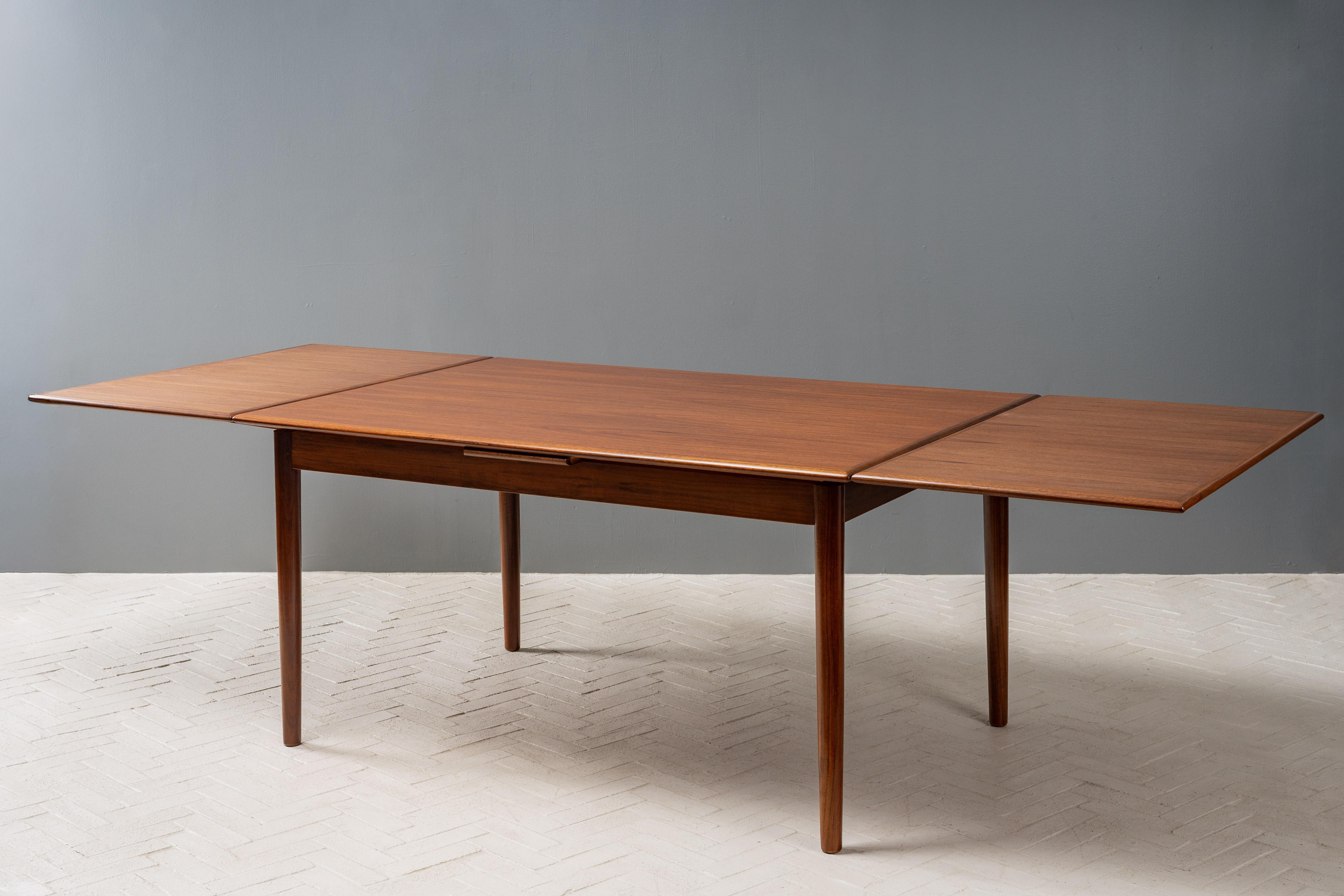 Denmark, ca. 1960s. A stylish and highly versatile dining table manufactured by Ansager Møbler. Features less common walnut construction with dramatically grained top and two self-storing, 23.75” pull-out leaves. Supported by minimalist turned and