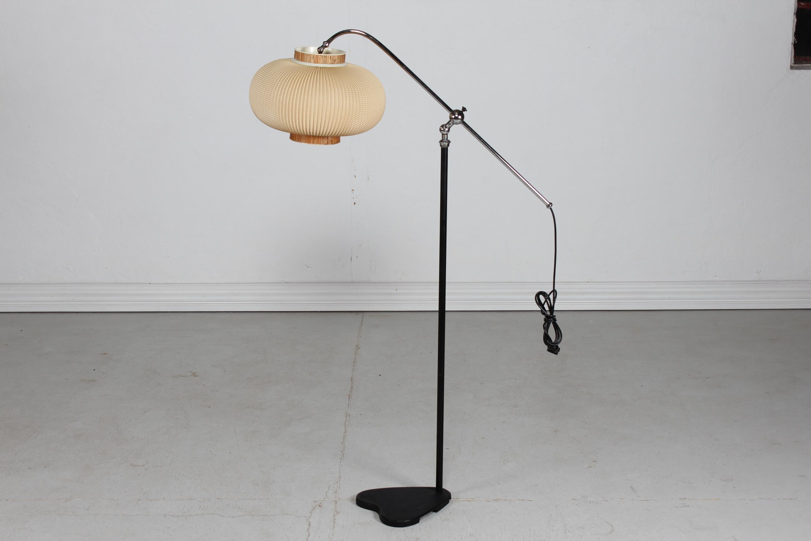 Art Deco height adjustable floor lamp made in the 1940s mounted with a Lars Eiler Schiøler shade from the 1960s.
The lamp has a duck foot shaped foot made of metal with black lacquer. 
The top part is made of chrome plated metal with a adjustable