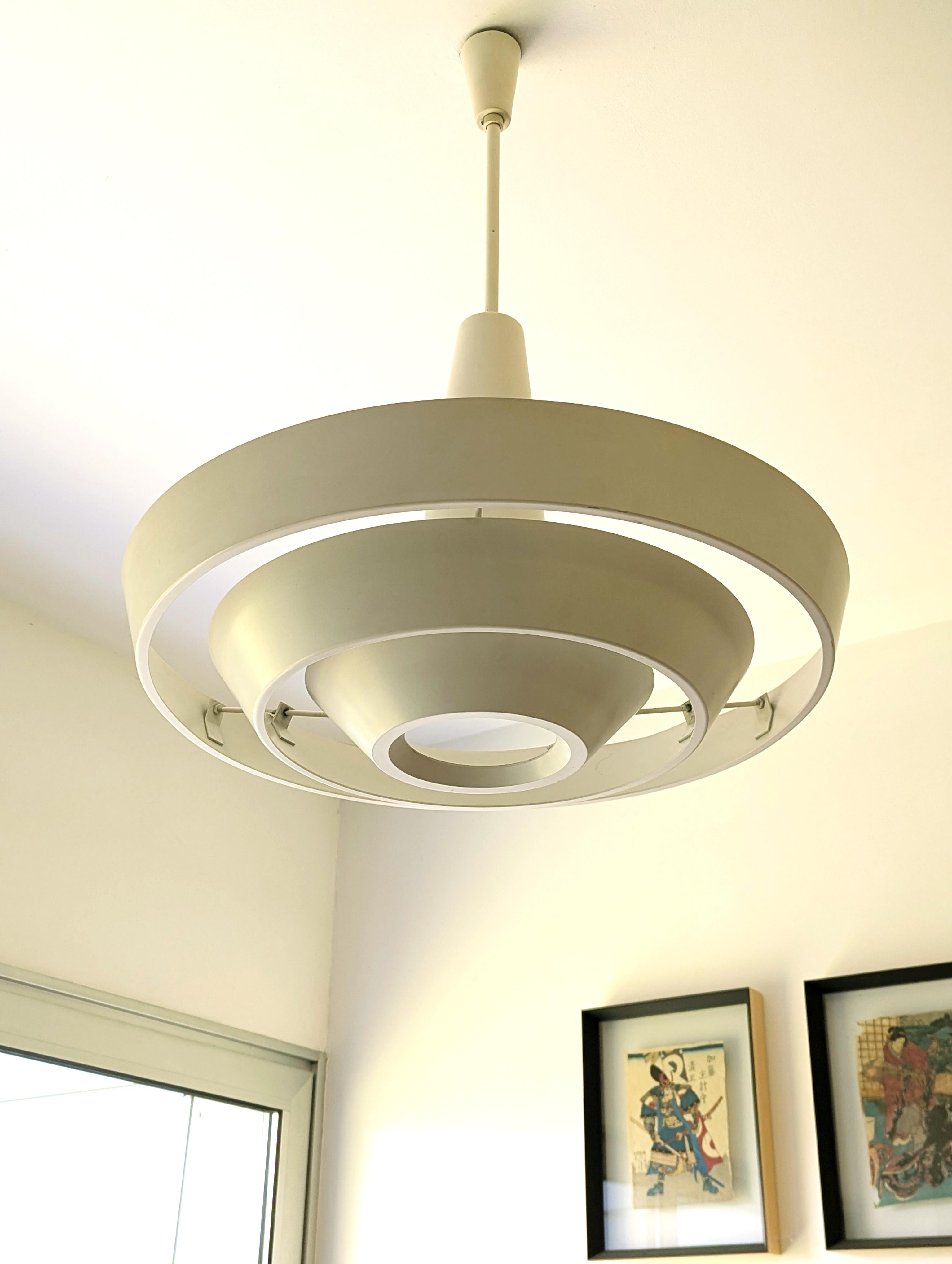 Rare and minimalist Scandinavian design chandelier produced by Regent in the 60s. White aluminum structure formed by concentric discs folded and supported to the main support through 3 chains. Original ceramic lamp holder. Slight deformation of