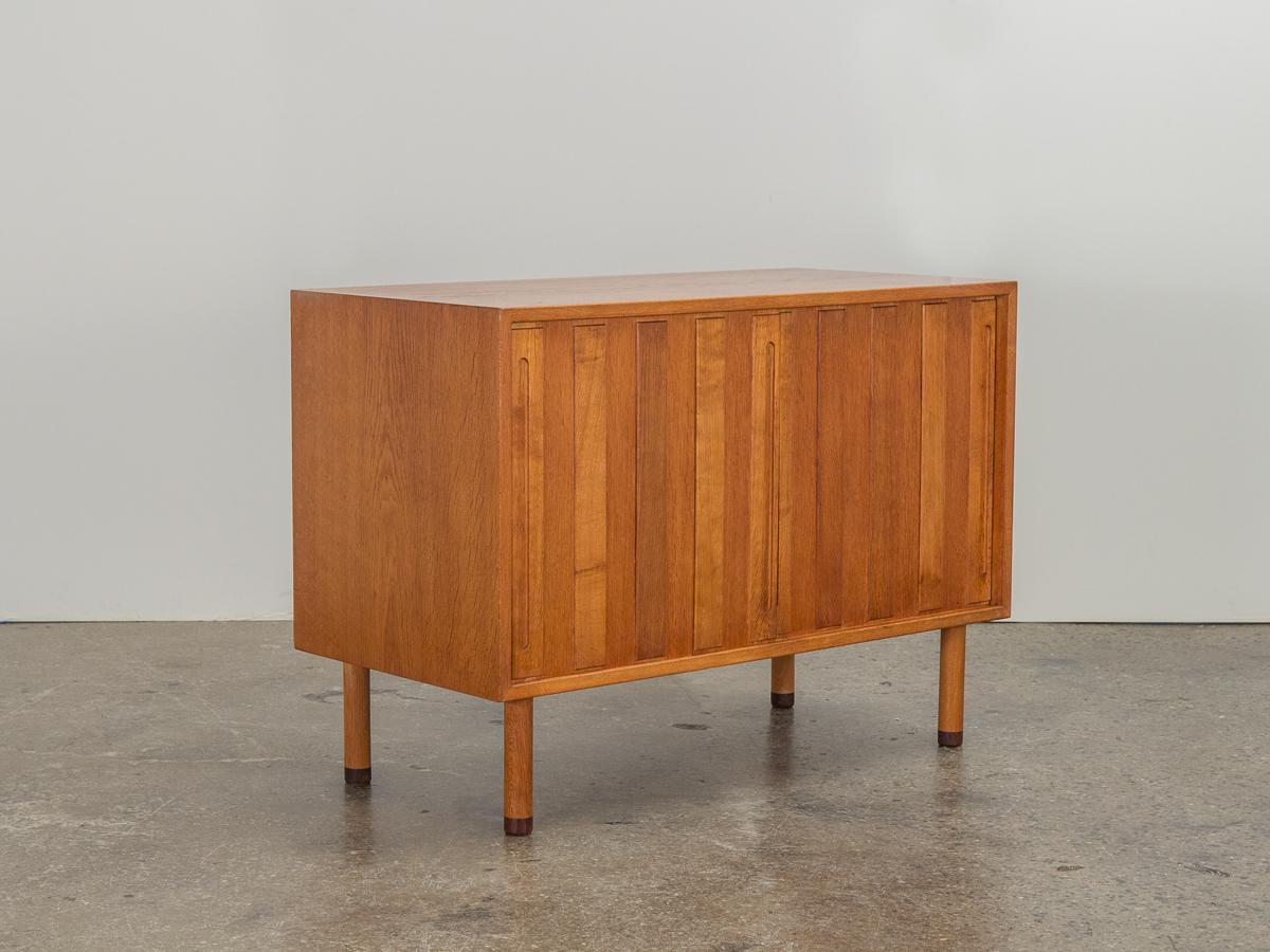 Seldom seen in this compact form, Danish white oak sliding door cabinet designed by Hans Wegner for Ry Møbler. This high-quality case piece has very interesting design details, including round feet capped with teak. Hand-pulls are inset at the