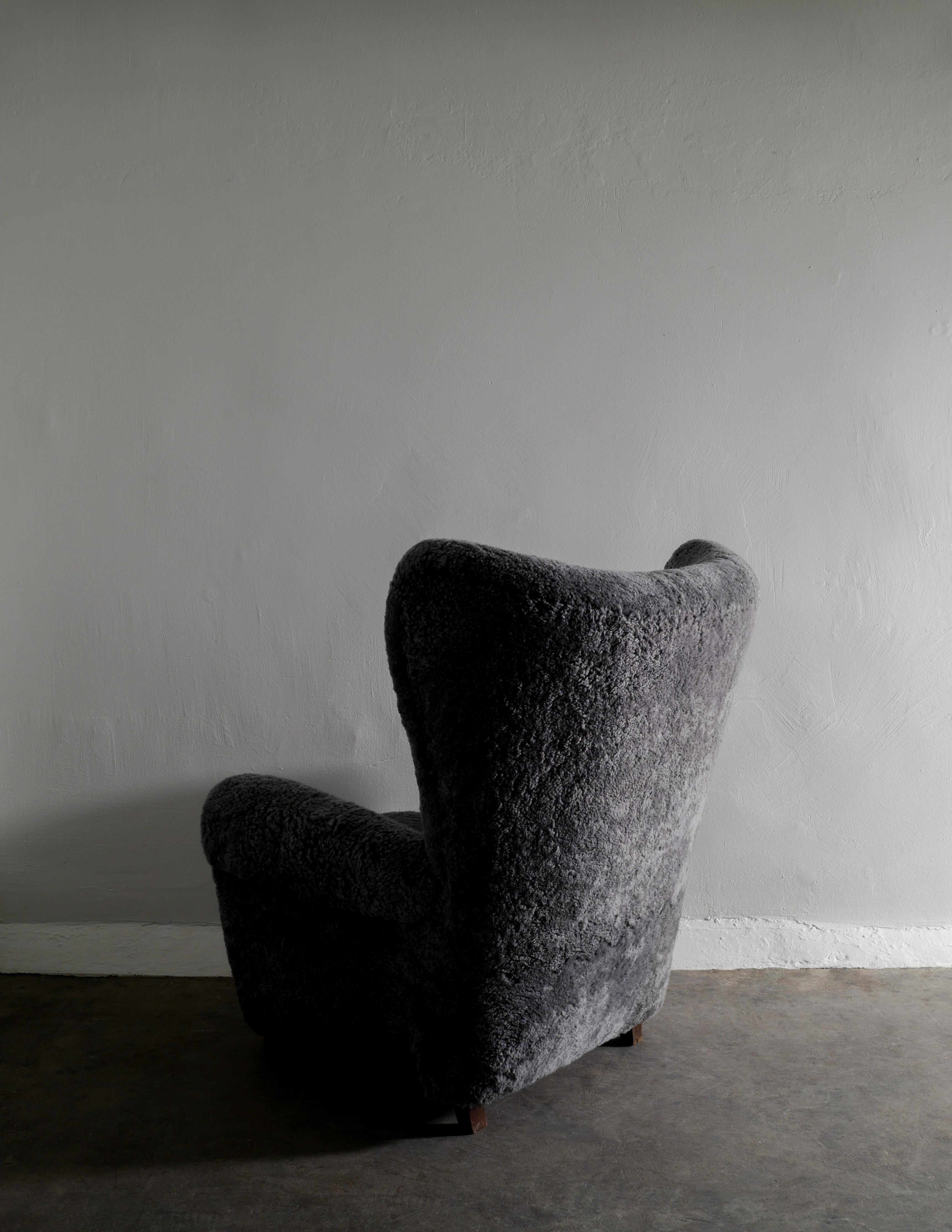 Rare wingback armchair in style of Fritz Hansen produced in Denmark ca 1940s. This chair has been newly restored and upholstered in a dark grey sheepskin and is it great vintage condition with small signs from age and use. 

Dimensions: H: 104 cm