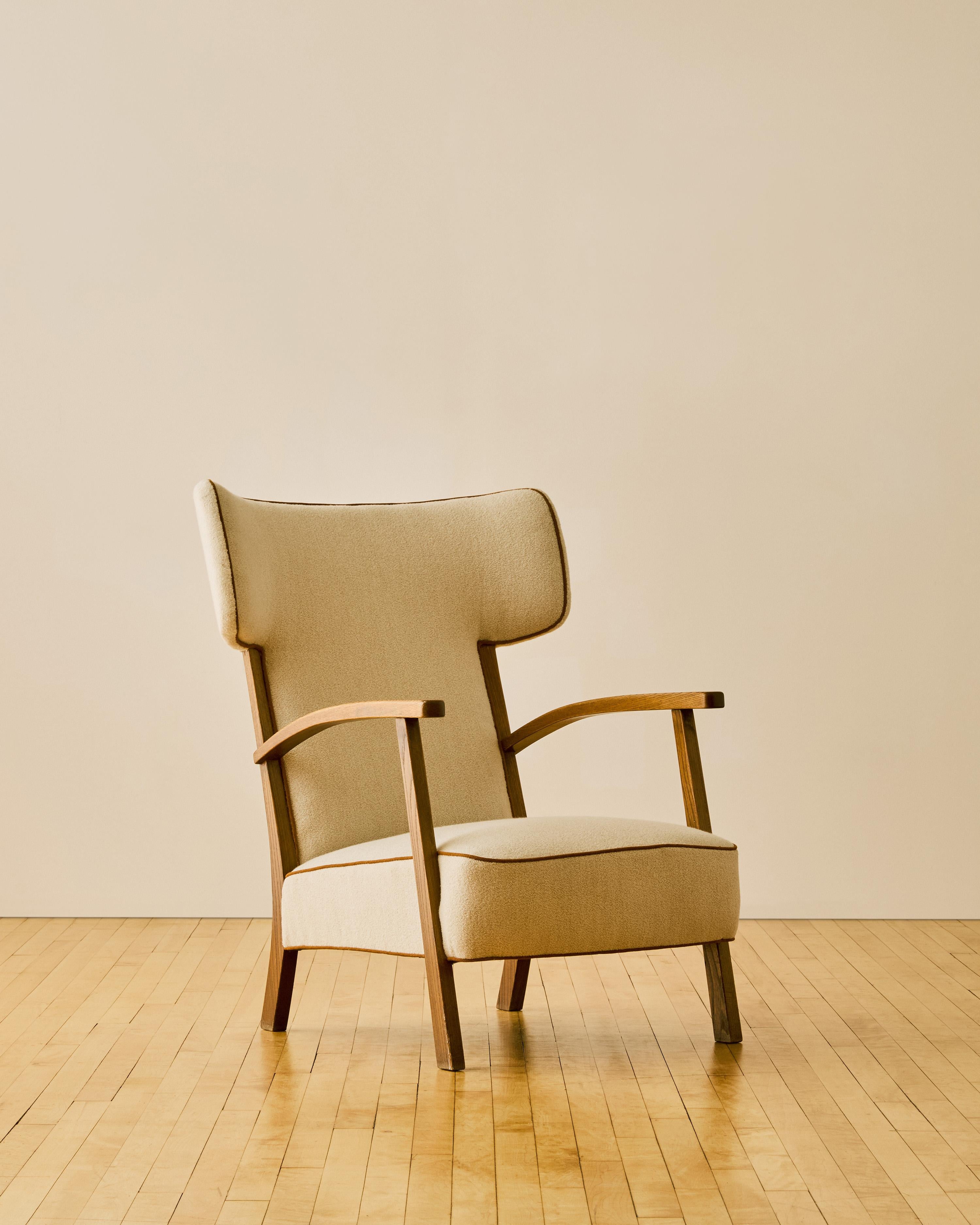 Sillón danés orejero c. 1950 recién retapizado en cachemira crema con ribetes en contraste y armazón de madera de fresno.