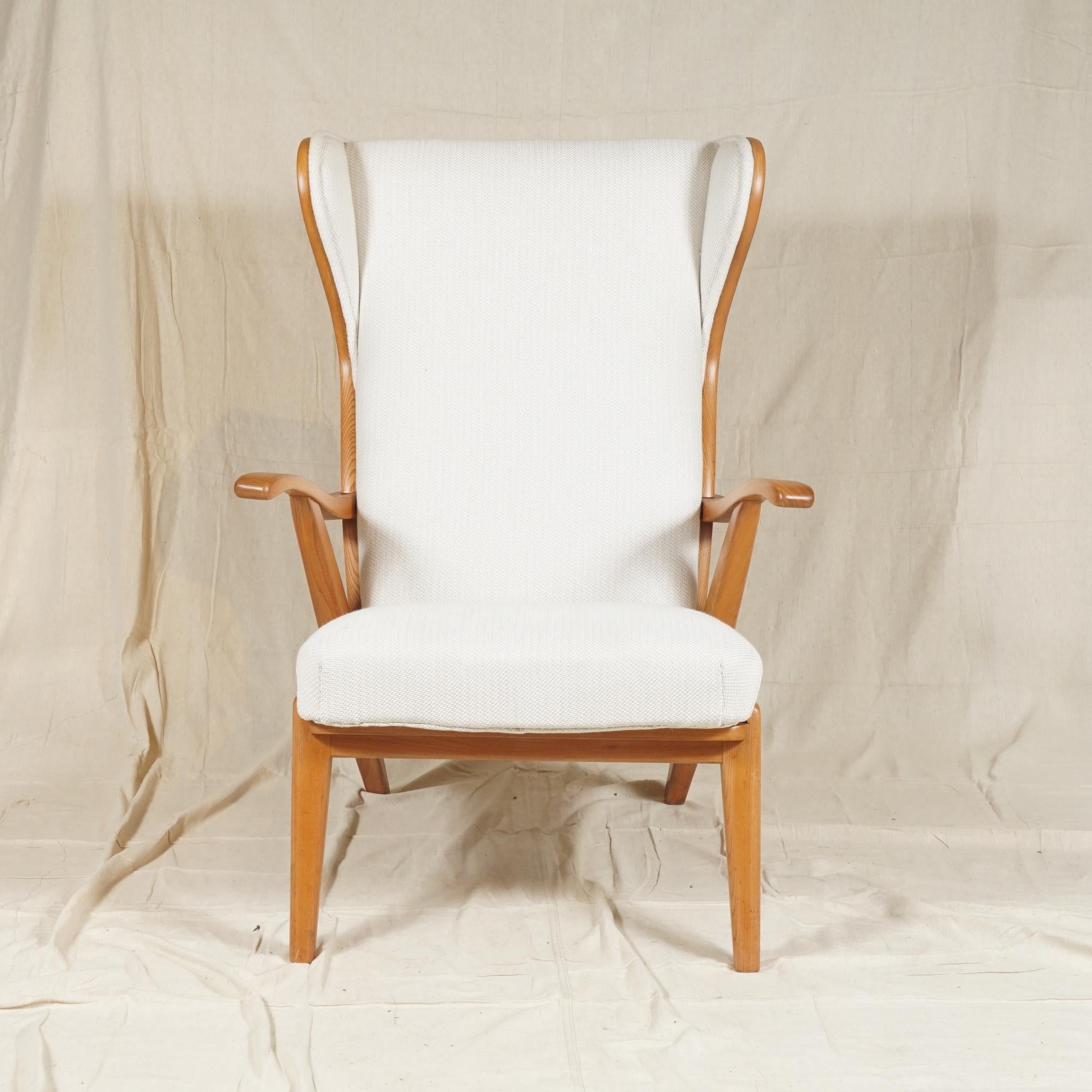 Very comfortable and distinctive wingback armchair by Danish cabinet-maker Søren Willadsen, with open curved arms and the back and wings encased in polished elmwood, on raised tapered legs.