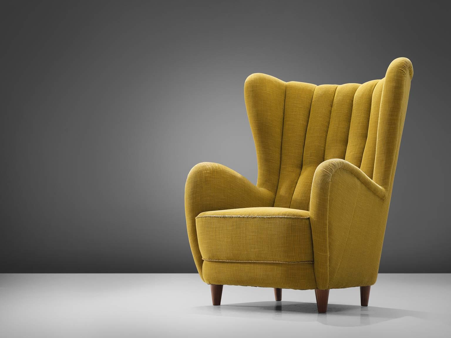 Danish cabinetmaker attributed to Mogens Lassen, wingback chair, stained beech legs, yellow fabric, Denmark, circa 1940

This easy chair has a grand wing and a sectioned back. The seat is thick and the armrests are thick, full and rounded. The