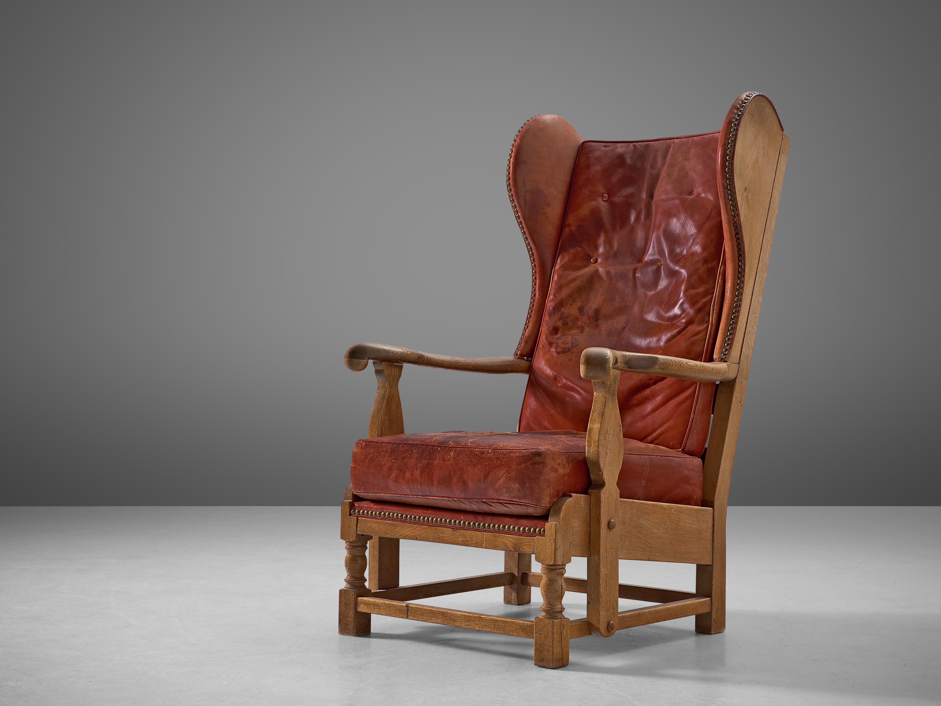 Lounge chair, red leather, oak, Denmark, 1930s.

This early Danish lounge chair features a voluminous wingback shape that gives the chair an elegant look. The 'ears' and armrest are beautifully formed. At the same time, the patinated leather red