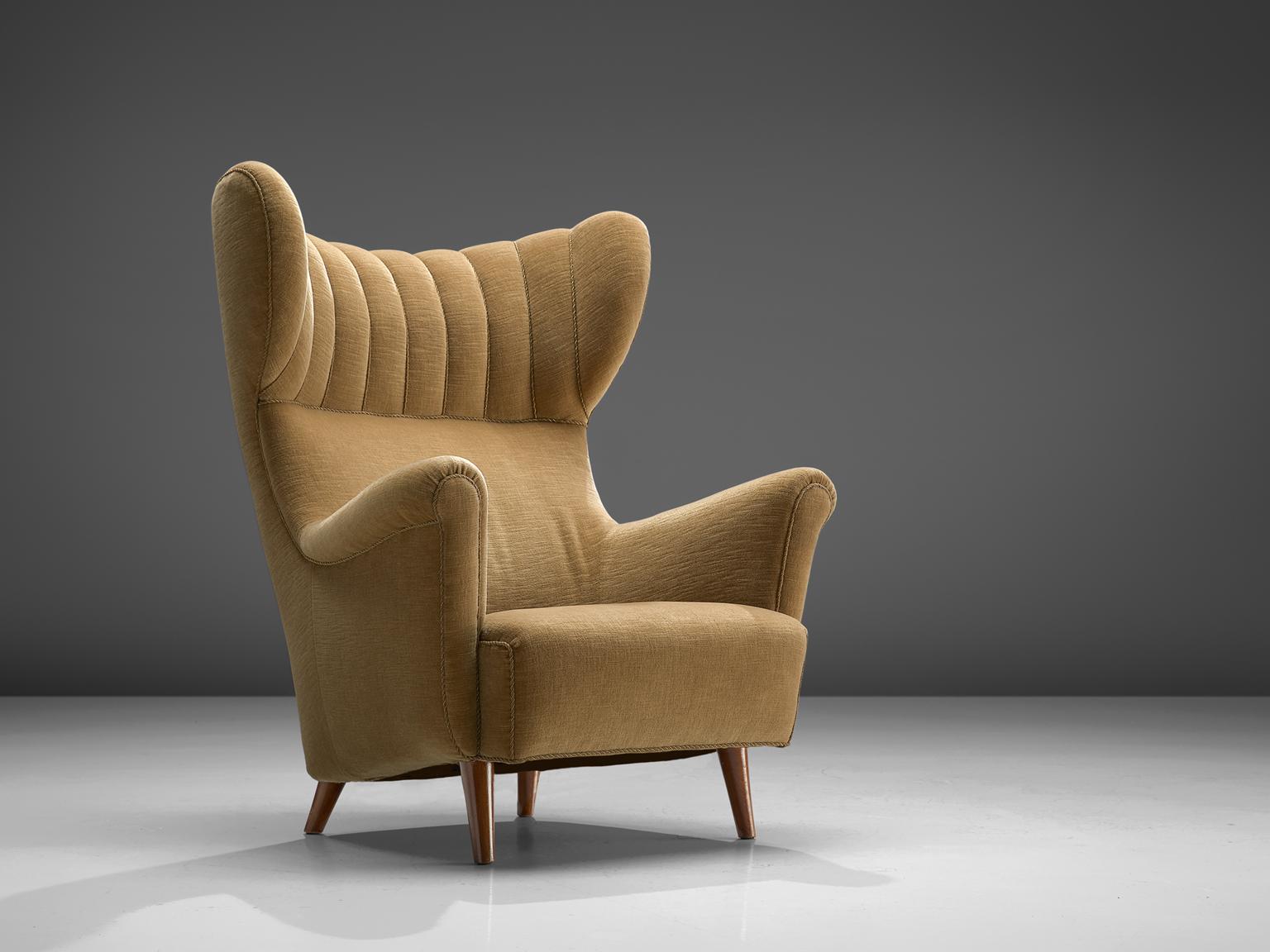 Wingback chair, pastel yellow velvet and teak, Denmark, 1940s

This voluptuous wingback chair with padded headrest and sloping armrests is typical for early Midcentury Danish design. The borders of this chair are finished with piping. The legs are
