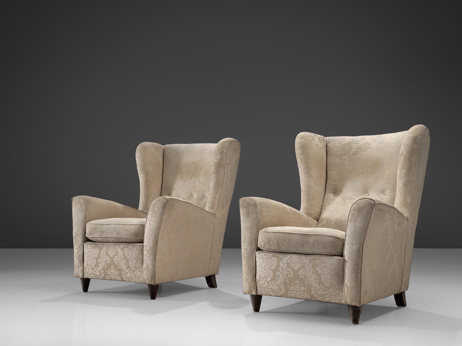 Pair of wingback chairs, stained beech legs, sand to off-white fabric, Denmark, 1950s. 

This pair of easy chairs has a grand wing and a buttoned back. The construction of the seat is based on delicate lines and curves that contribute to the chair's