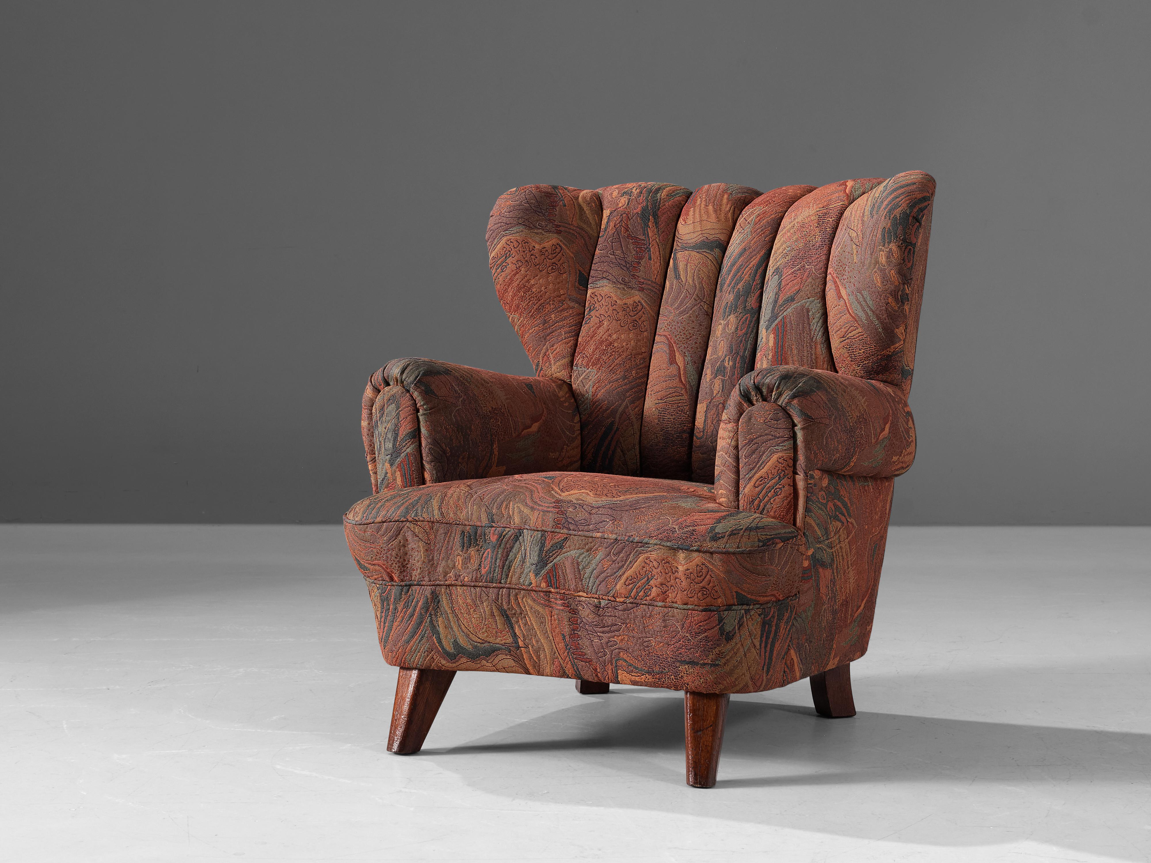 Easy chair, fabric, wood, Denmark, 1950s

This lovely and comfortable Danish chair features wings and curved armrests. Thanks to its voluptuous armrests and seating, the chair gets a characteristic, visually interesting shape. This is emphasized by