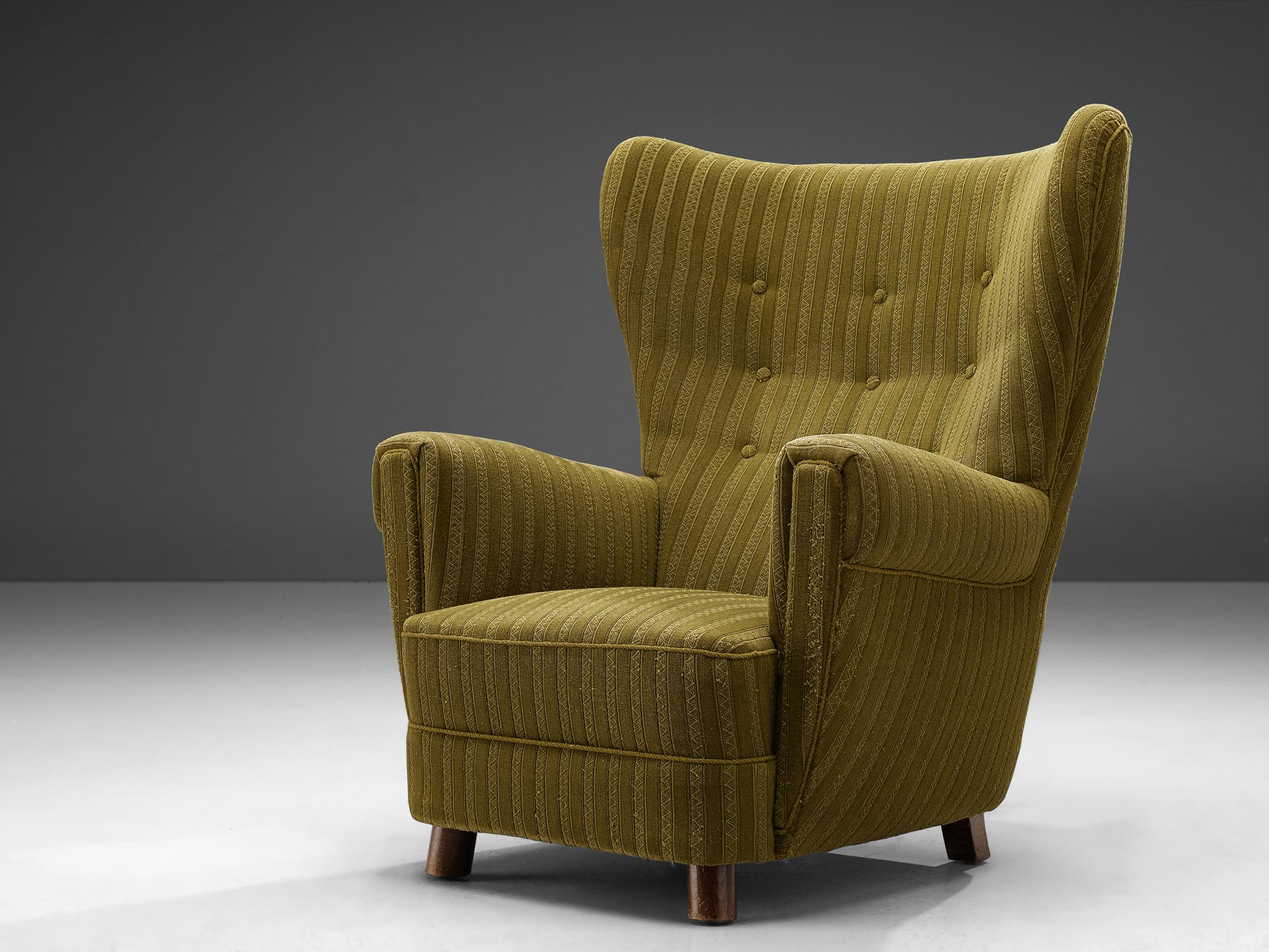 Wingback armchair, green striped upholstery, wood, Denmark, 1950s.

This Classic Danish wingback chair is upholstered in a green striped fabric and is finished with green piping and a tufted backrest. The rounded shape of the backrest and seat give