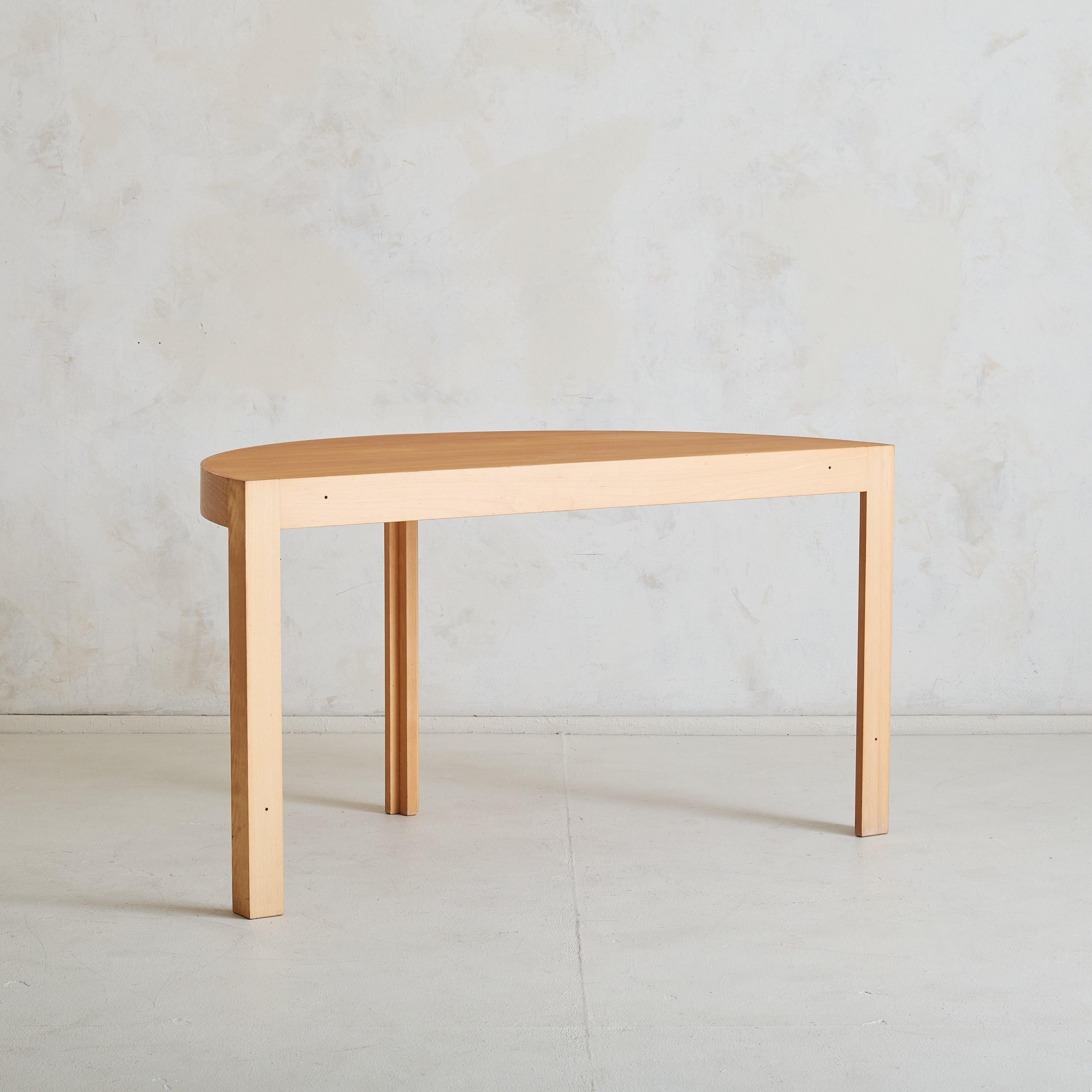 A 1960s Danish demilune console table, designed by Johnny Sørensen and Rud Thygesen for Botium. Crafted from warm-toned wood, the table’s half-moon top is supported by three angular legs. With clean lines and a minimalistic silhouette, this piece