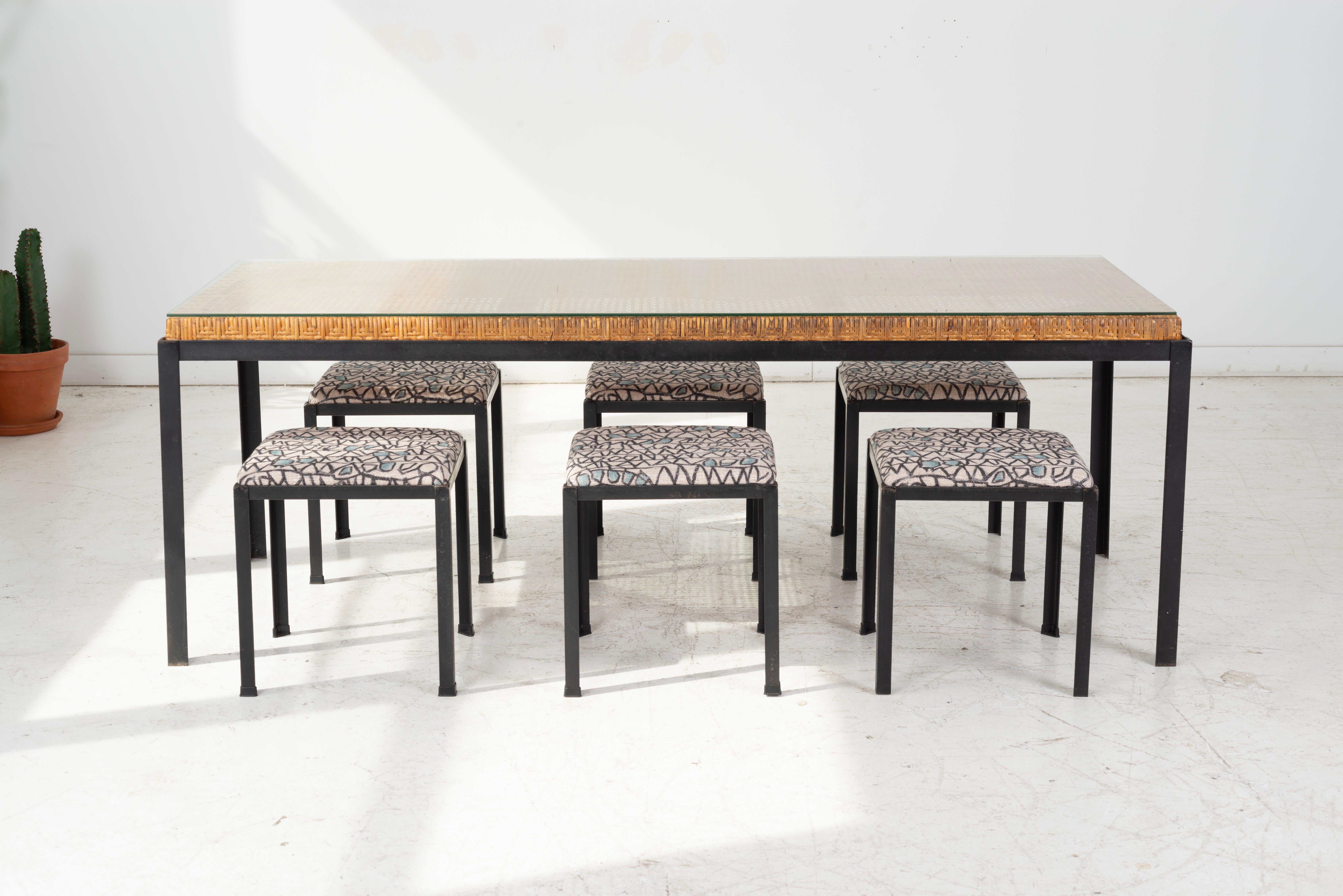Danny Ho Fong, the king of wicker designed this dining set with 6 stools. Dining table base and stools are made of iron.  The table top is a strong wicker structure, with a thin glass top.  Stools have been Newley upholstered with a patterned canvas