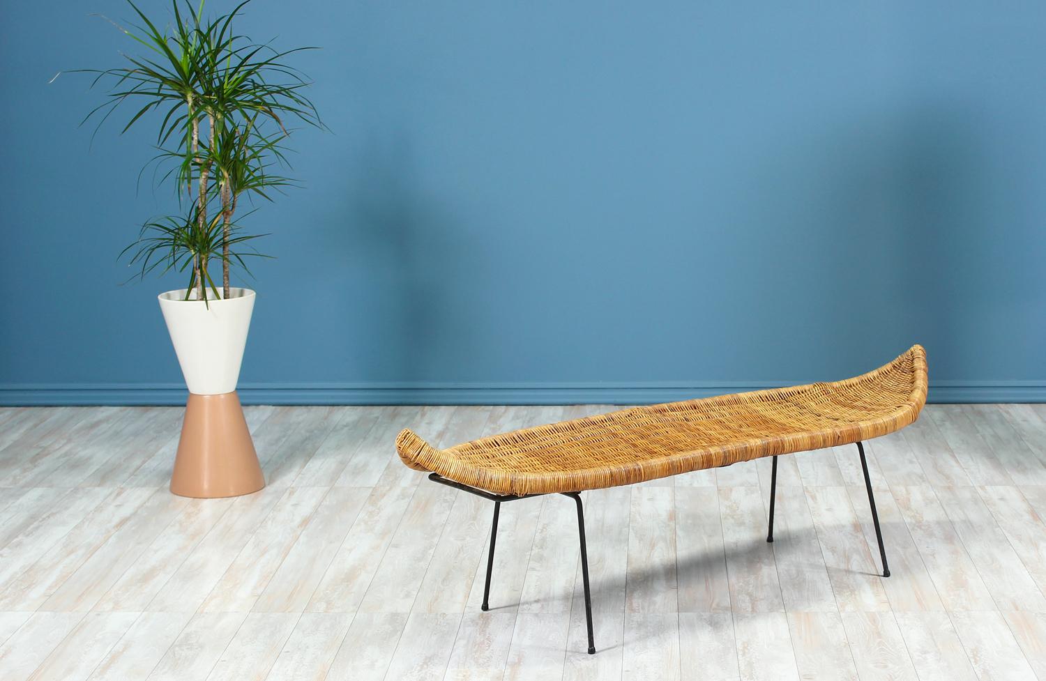 Spectacular cane bench designed by Danny Ho Fong for Tropi-Cal in the United States circa 1960’s. This fabulous Mid-Century Modern bench maintains its original intricately woven wicker seat rest and iron base to preserve its vintage value. The seat