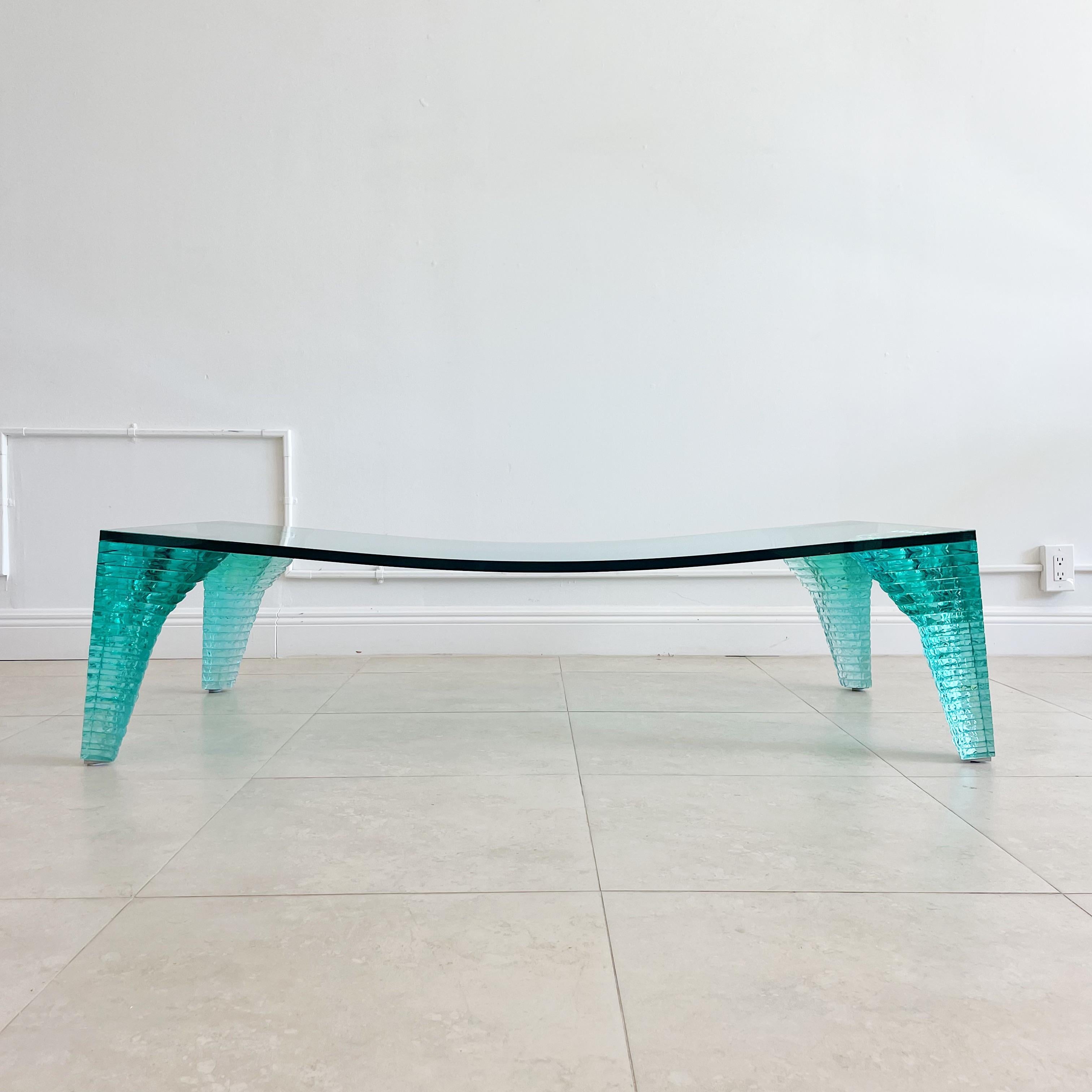 A Danny Lane “Atlas” coffee table. A clear green piece of concave glass set on four graduating stacked glass legs. Designed by Danny Lane for Fiam. Italy, circa 1980. 
Danny Lane (born 27 January 1955) is an American artist, best known for his