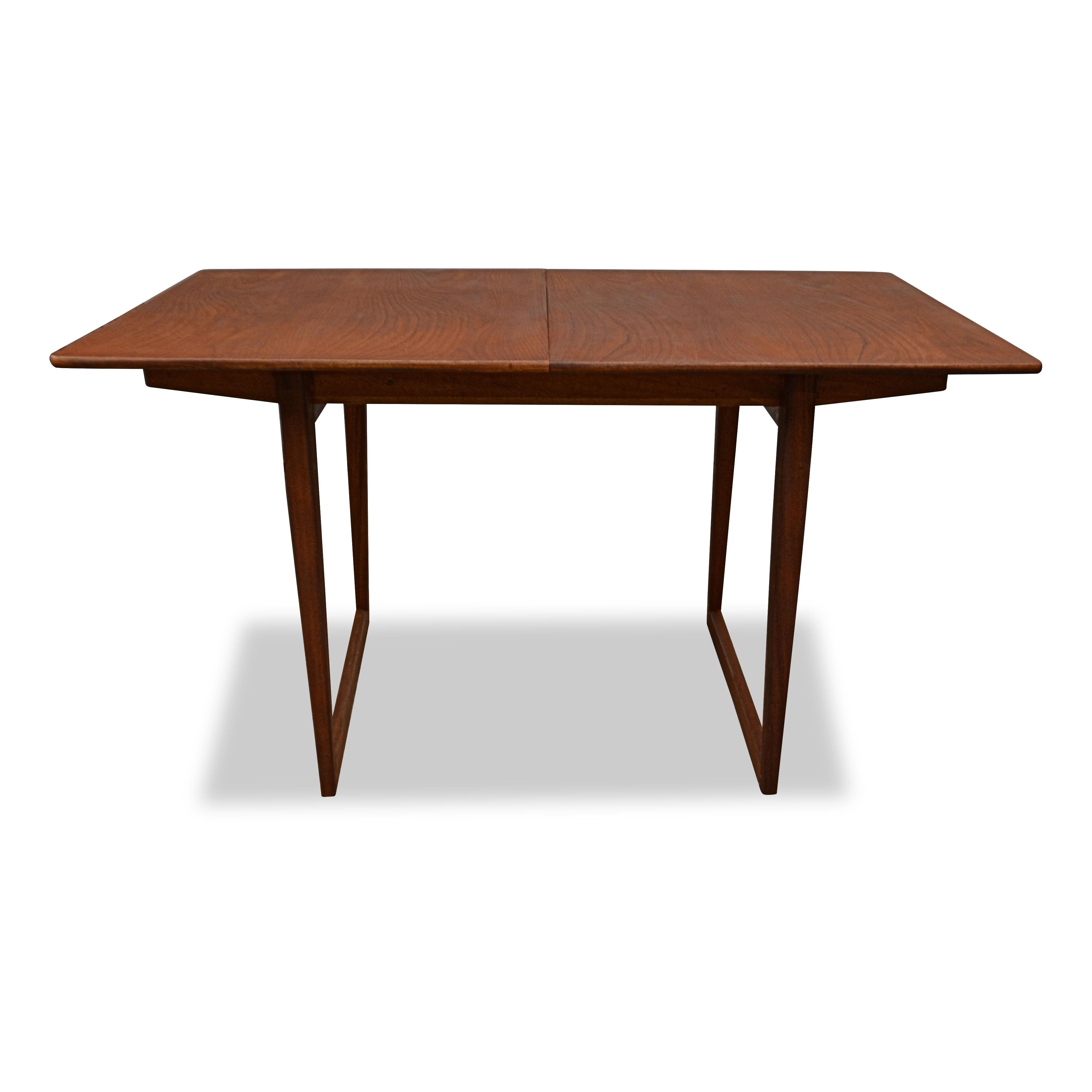 Stylish vintage Danish teak dining table by an unknown designer. This rare table features a beautiful sled base and a fold-out extension piece with brass hinges. The extension piece disappears under the tabletop when folded in. When extended you’ll