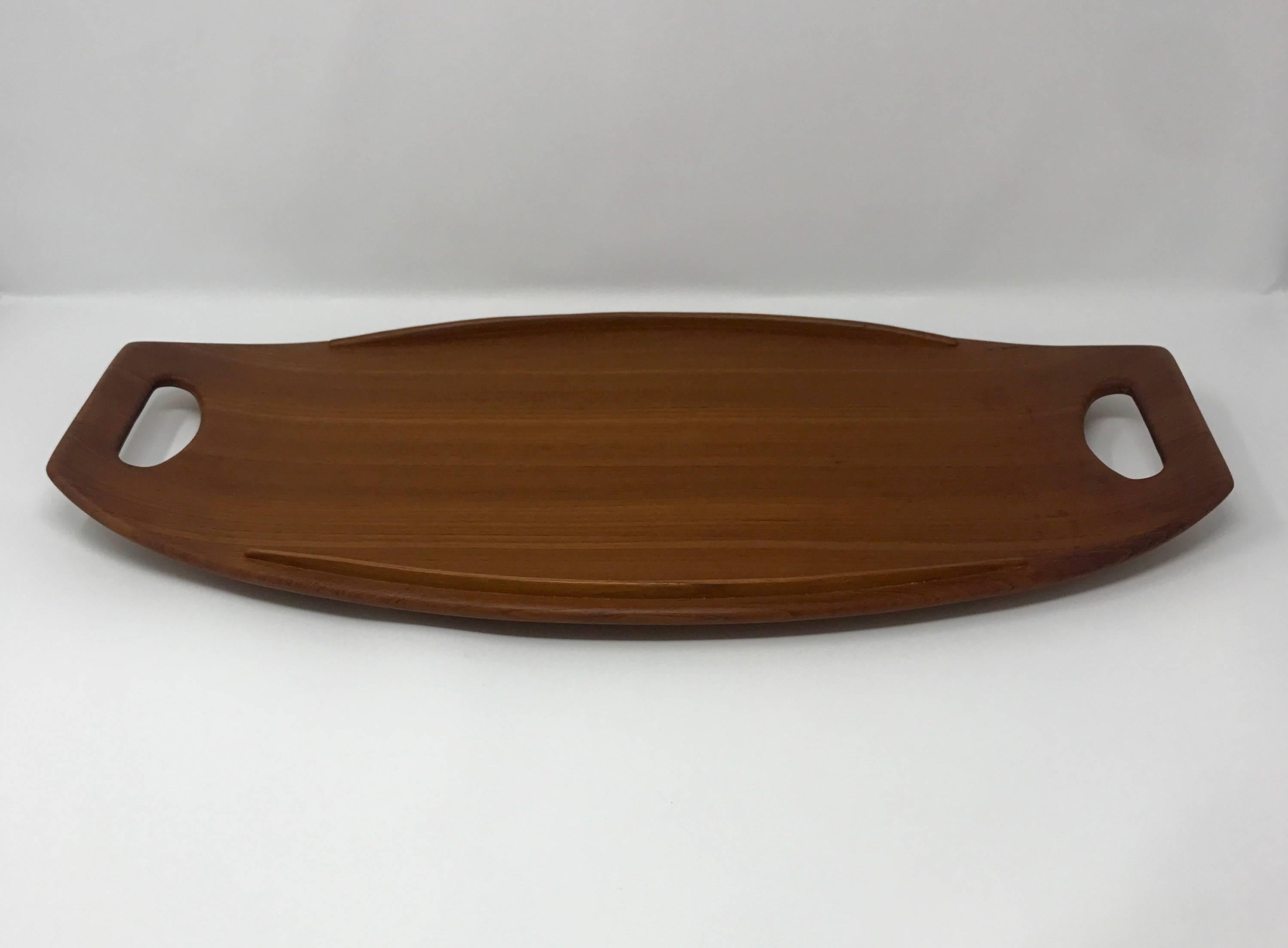 Danish modern teak serving tray, model 801, designed by Jens Quistgaard for Dansk. The tray is elegantly tapered, with raised side rails. Marked with the model number and Dansk logo on the underside.