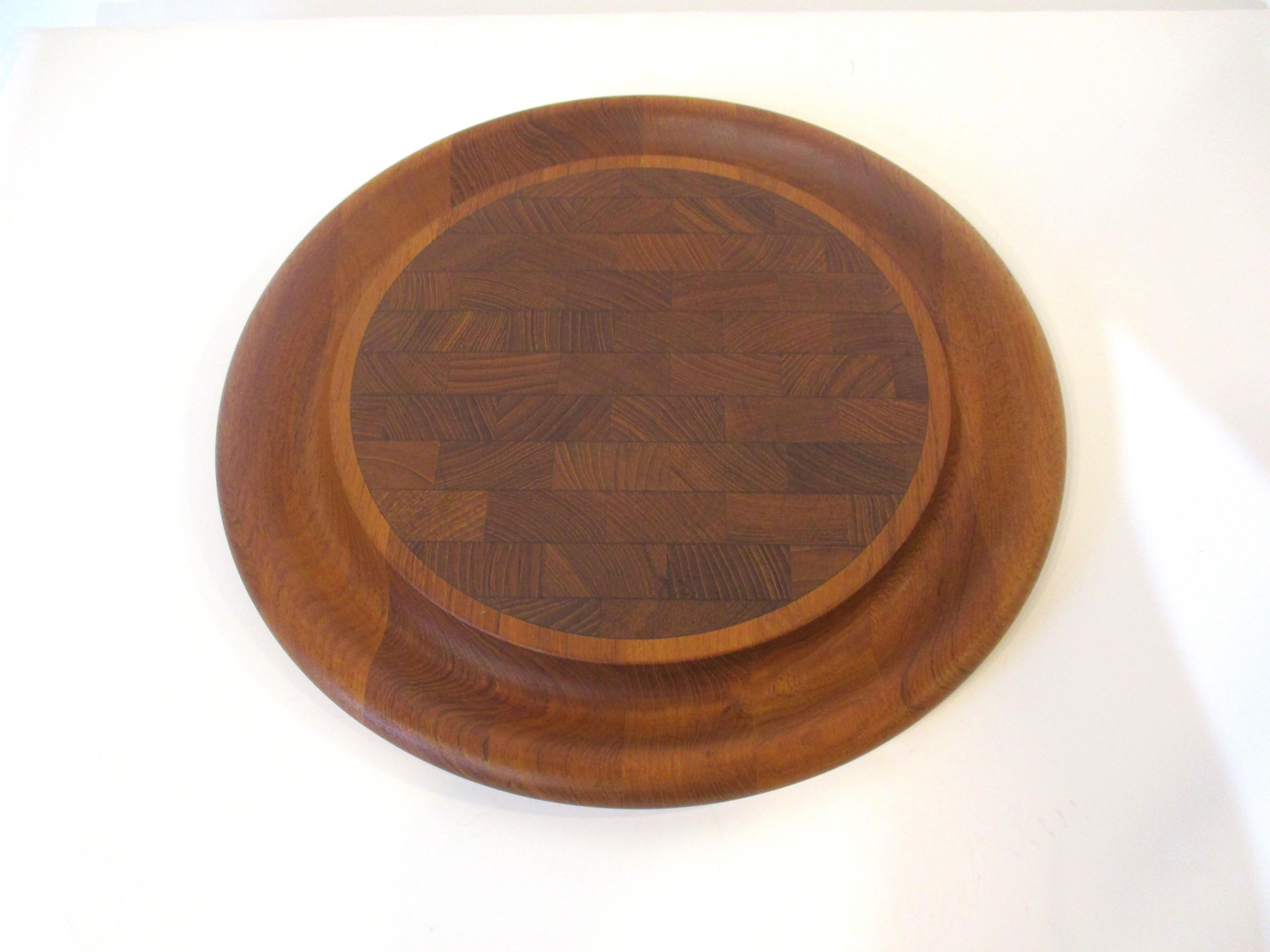 A very well crafted teakwood cheese and charcuterie board with center platform for the goodies and a lower rim for bread or crackers . Designed by Jens Quistgaard for Dansk noted for their great designs and simple elegance, made in Denmark.