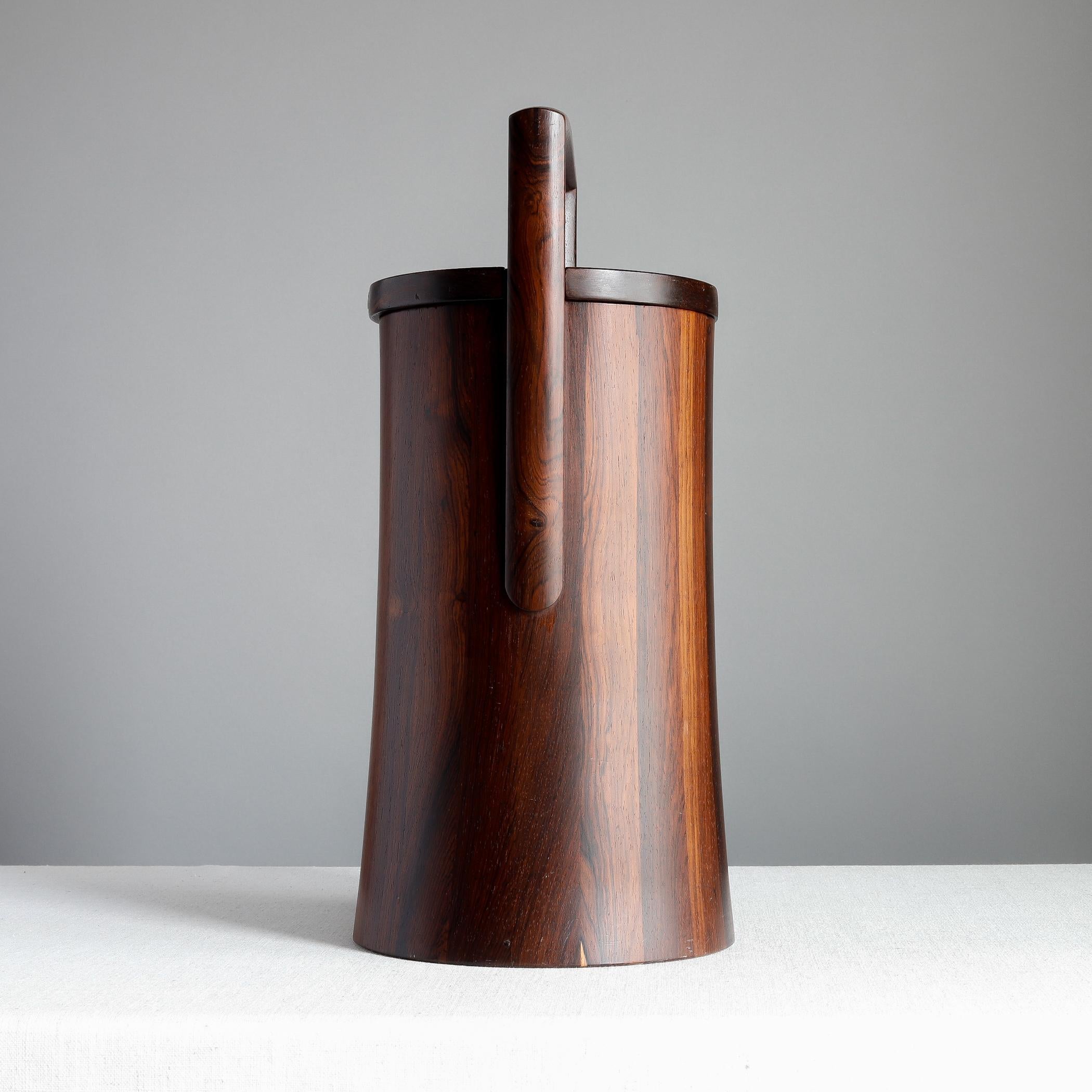Staved palisander ice bucket designed by Jens Quistgaard for Dansk. This is from the 'Rare Woods' line, a group of wares made from exotic woods from around the globe, dating to the early 1960s. The lid fits snugly and tilts to lift out, black