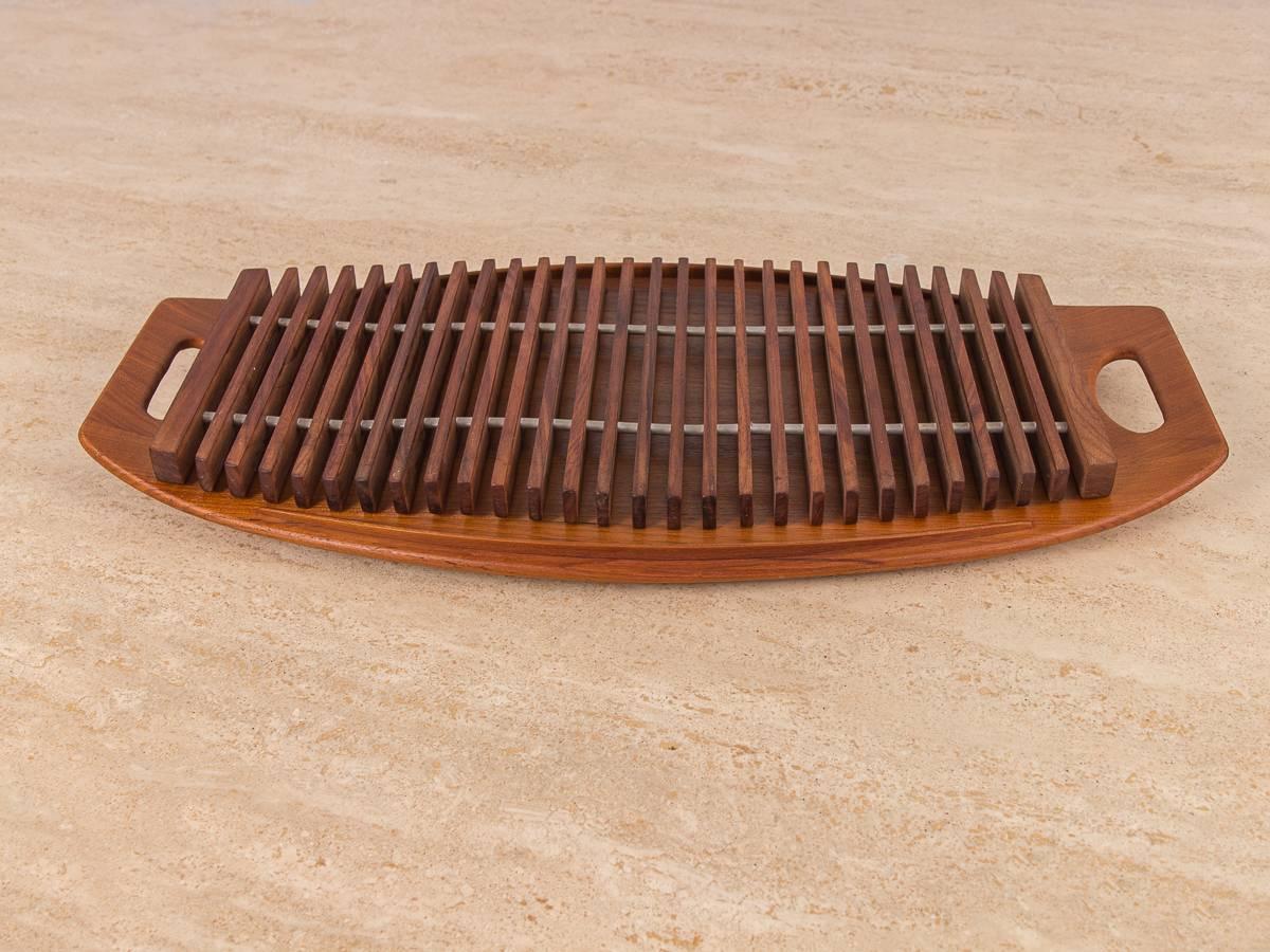 Dansk serving tray with rarely seen inlay trivet by Jens Quistgaard. Use with or without the trivet for Dual serving purposes. The trays edged have a carved, raised lip to prevent slipping or spilling. Gleaming teak wood is in excellent vintage