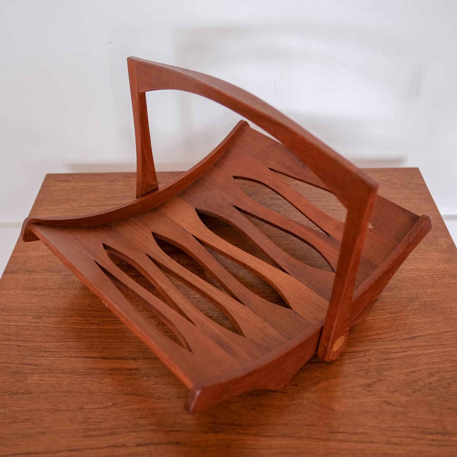 Magazine rack designed by Jens Quistgaard for Dansk. Staved solid teak frame with collapsible handle. Branded on the bottom with JHQ and early Dansk logo. Excellent joinery detailing. Denmark, 1960s.