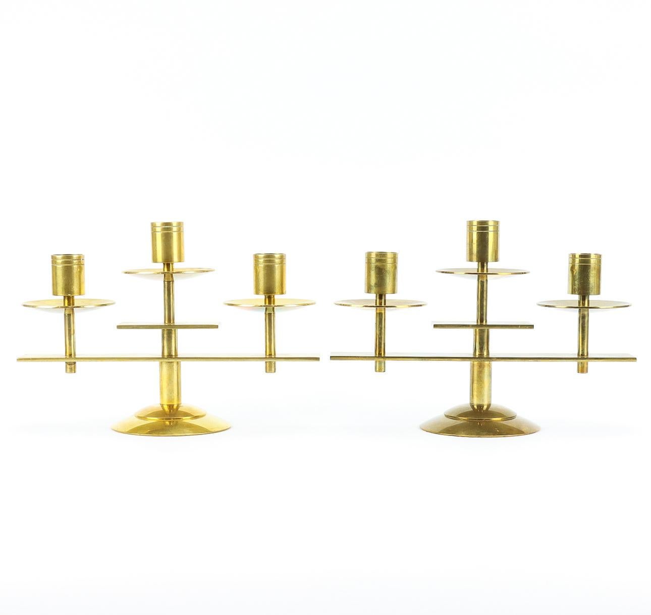 An elegant pair of three-branch brass candlesticks with bobèches, designed and manufactured by Dantorp Design in Denmark in the 1960's. Each is stamped 