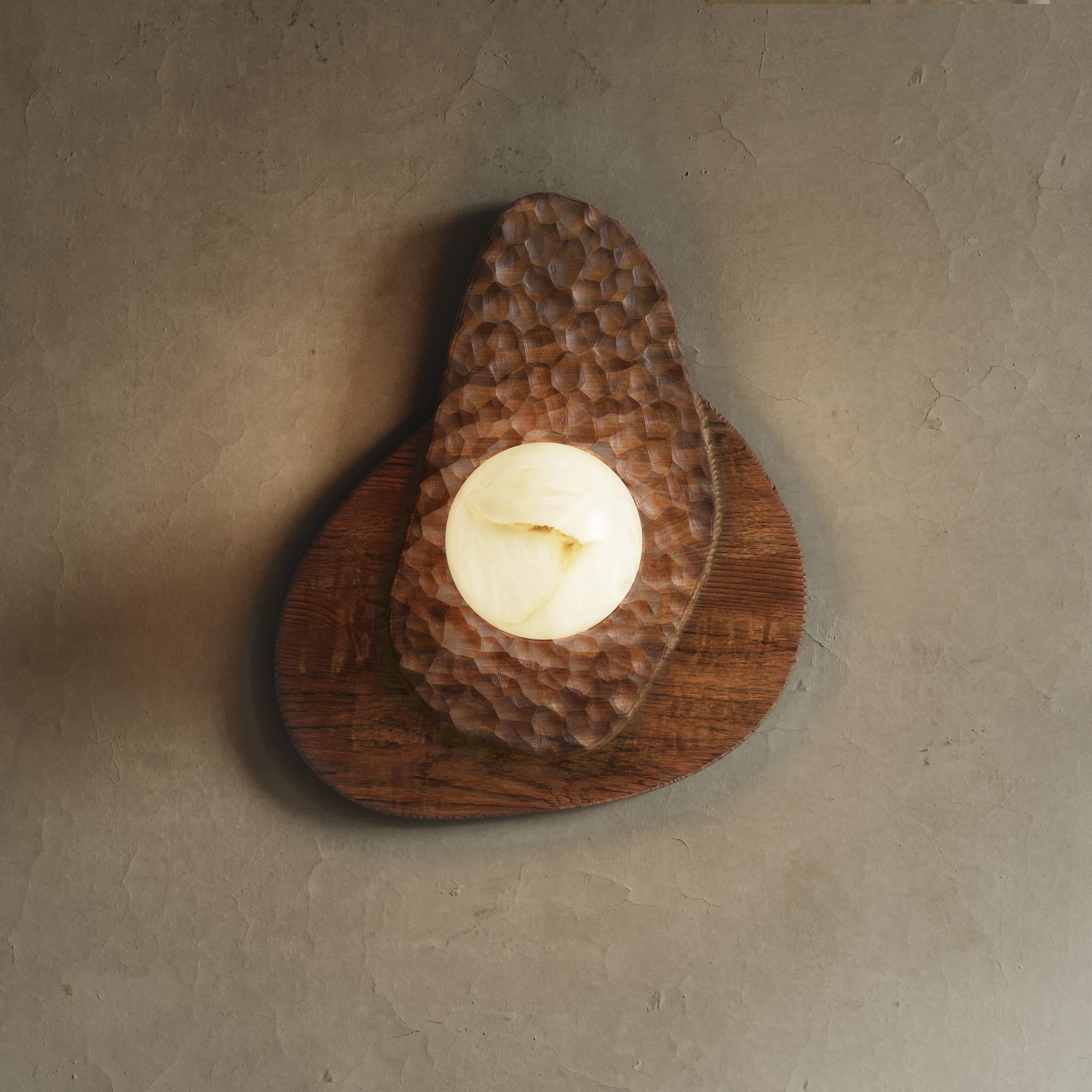 The Daphne Wall Sconce is an exquisite handcrafted lighting fixture that combines solid wood and alabaster globe for a unique appearance. The sconce is made using traditional techniques such as hand carving, ensuring that each piece is one-of-a-kind