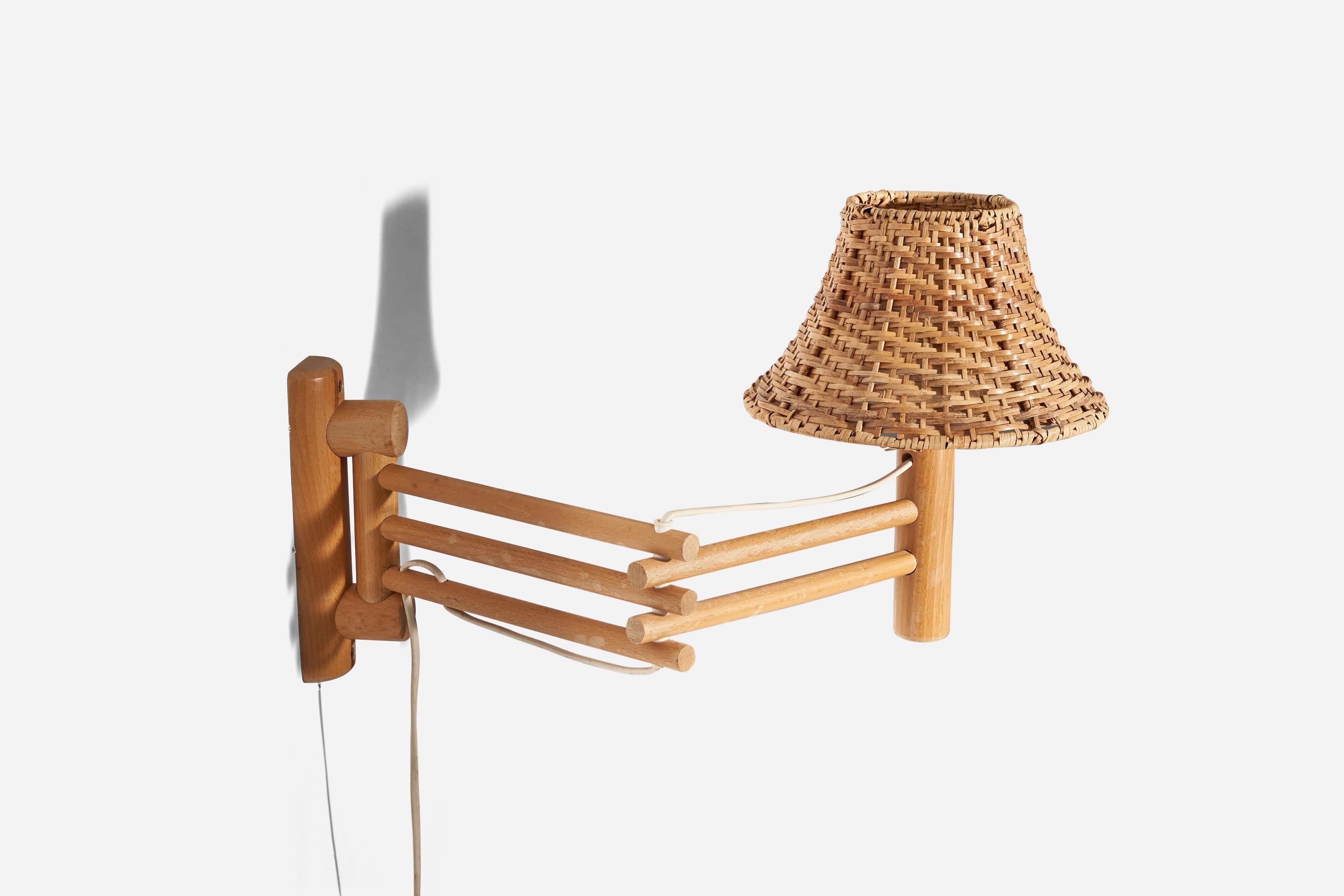 A rattan and oak wall light designed and produced by Darø, Denmark, 1960s. 

Sold with Lampshade. 
Stated dimensions refer to the Sconce with the Shade. 
Variable dimensions, measured in the lamp's maximum extended position.