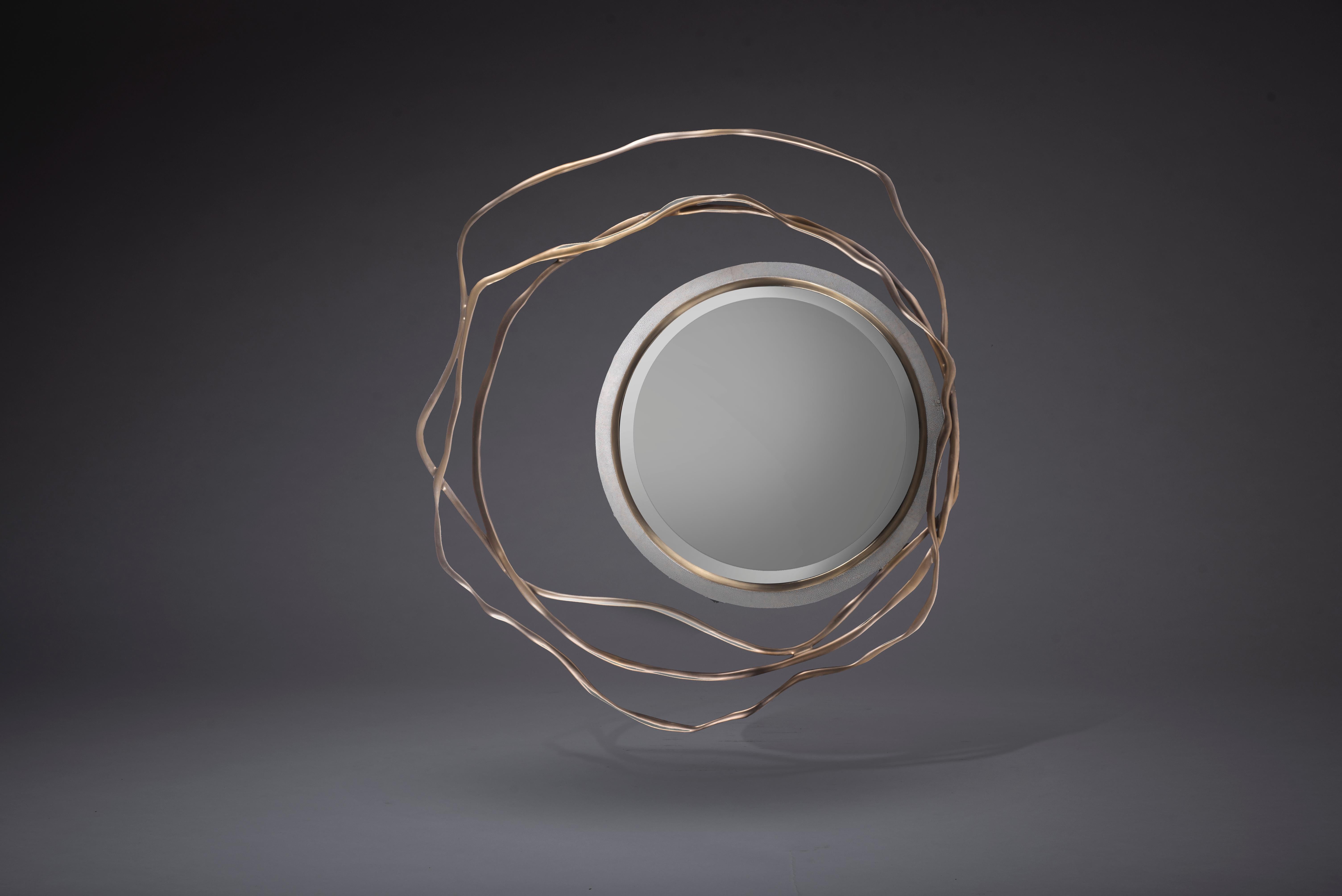 Der Spiegel Dargelos ist mit seinen ätherisch inspirierten Wurzeln ein Statement. Die Verflechtung der gedrehten Messingdrähte aus Bronze und Porzellan mit dem kreisförmigen, cremefarbenen Rahmen des Spiegels schafft eine wahrhaft skurrile