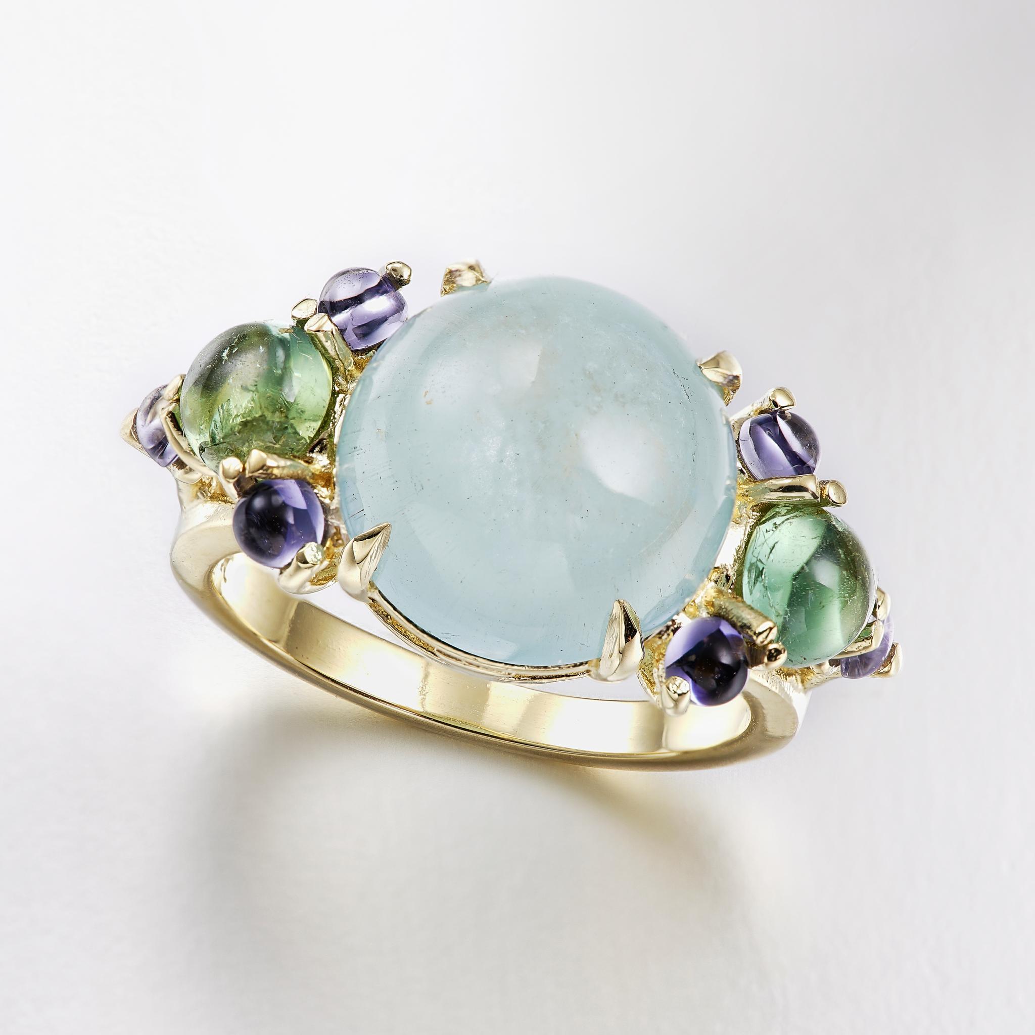 A luxurious cocktail ring in 18 karat yellow gold featuring a claw set 12mm round aquamarine center stone, with prong set green tourmaline and iolite gems on both sides of the stone to complement.

This ring can be sized to fit your finger. Please