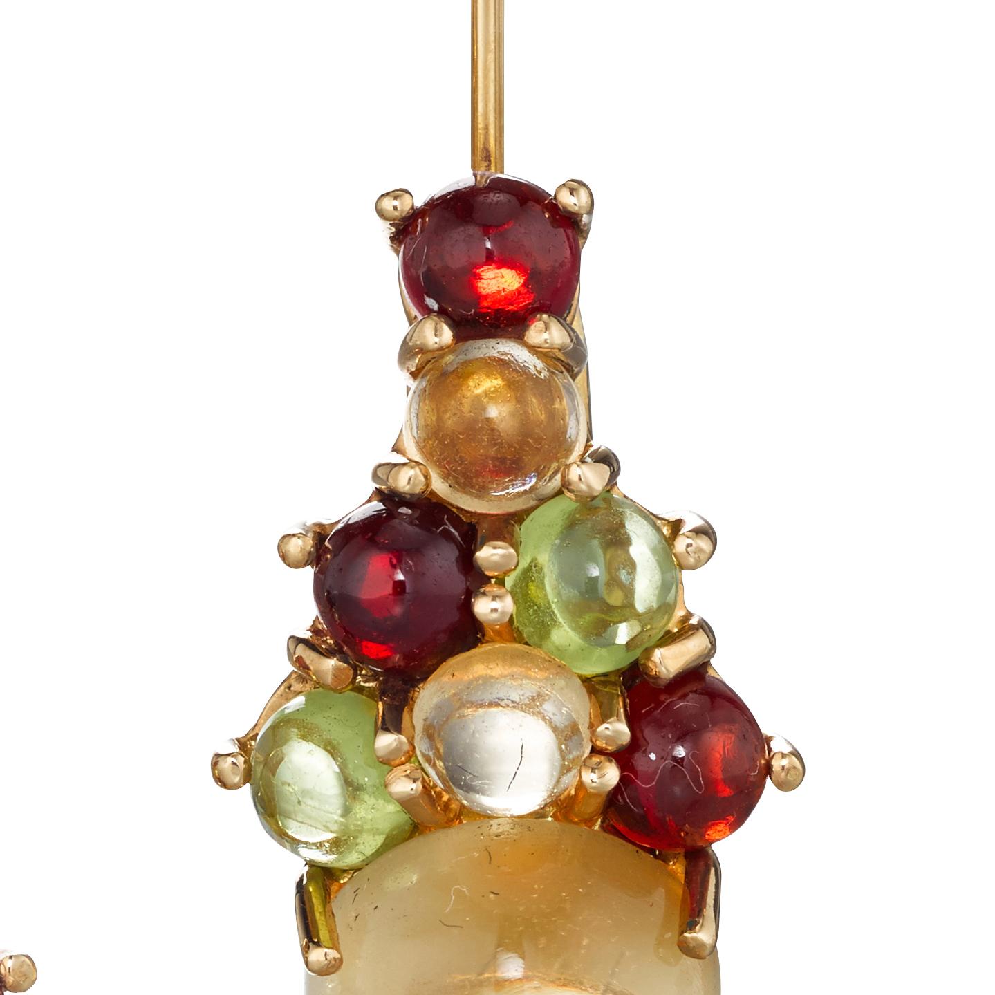 A colorful bundle of stones suspended from a delicate wire. Set in 18k yellow gold, a medley of peridot, citrine, red garnet, pale blue topaz sit atop an 8mm cabochon-cut citrine. For pierced ears.

Daria de Koning’s one-of-a-kind cabochon-centric