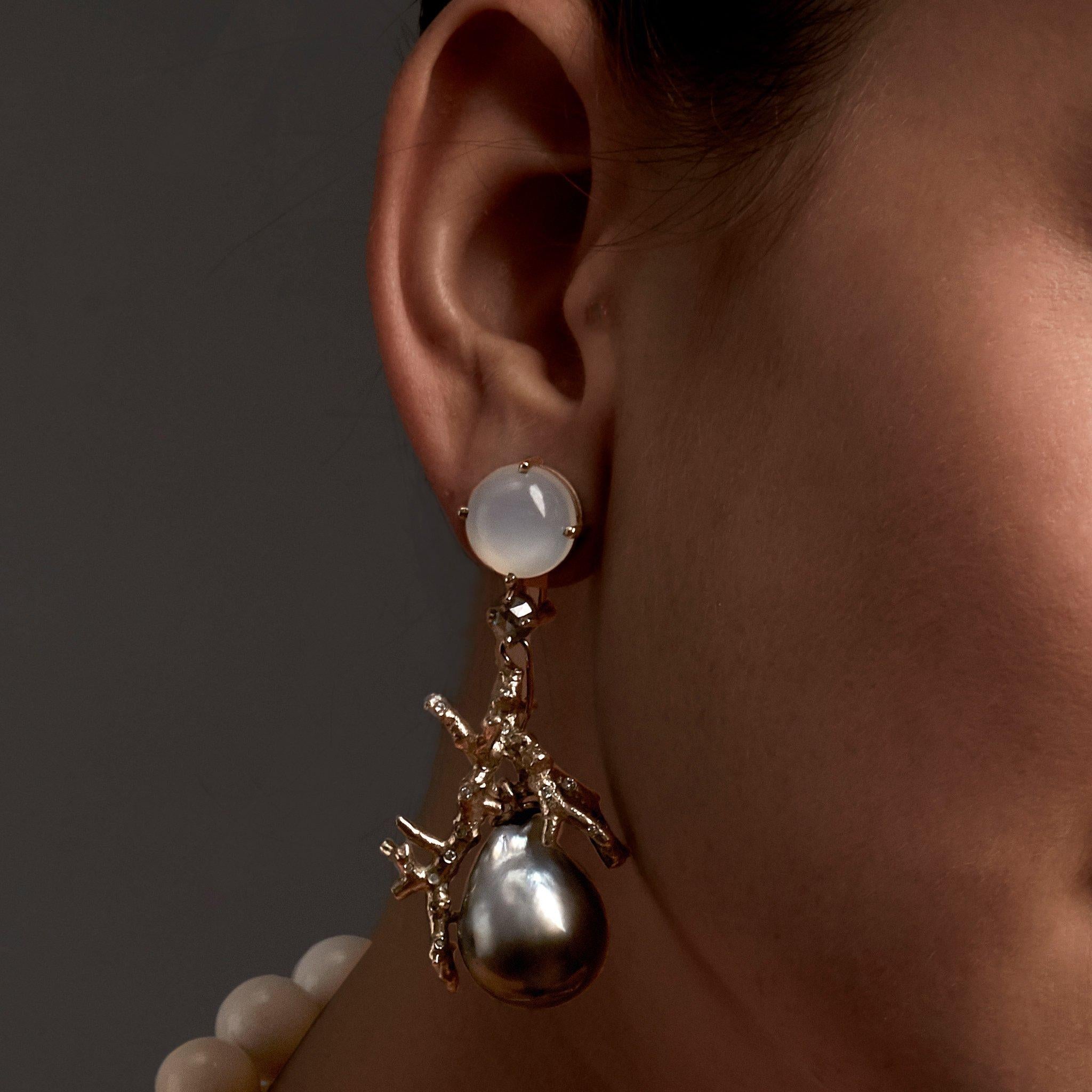 Elegant statement earrings feature opposites of cabochon-cut, dark grey and white moonstones married with rose-cut 