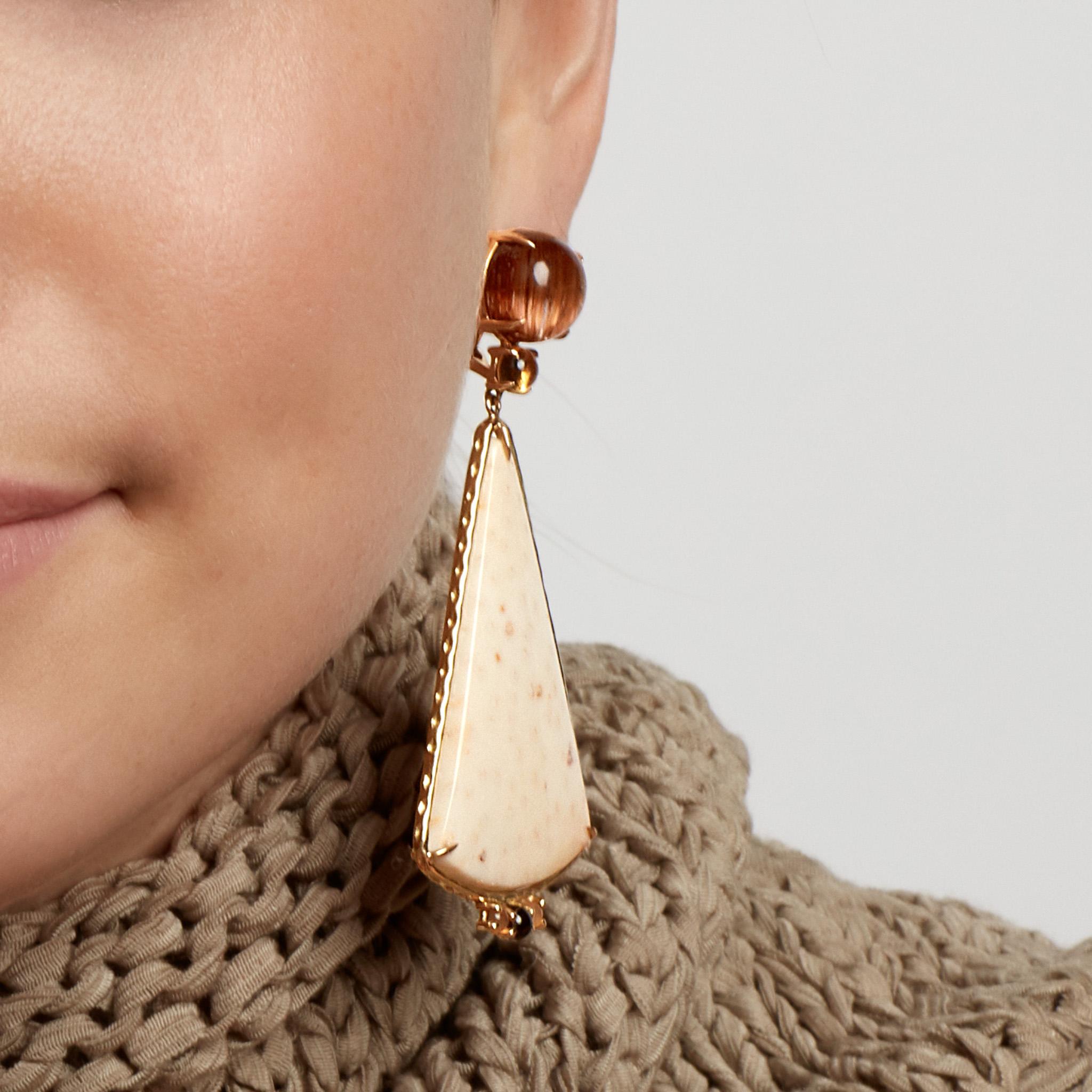 These Daria de Koning earrings feature impressive cabochons tops of caramel-colored rutilated quartz and citrine. Glamorous triangles of petrified palm wood sway gently below, highlighted with trios of pale smokey citrine and carnelian. Set in 18k