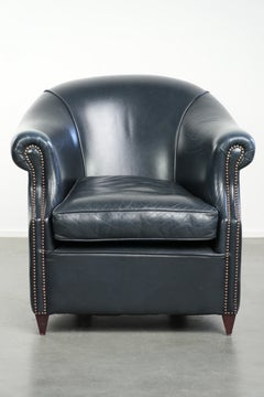 Fauteuil club en cuir de vachette bleu foncé au design unique et intemporel.
