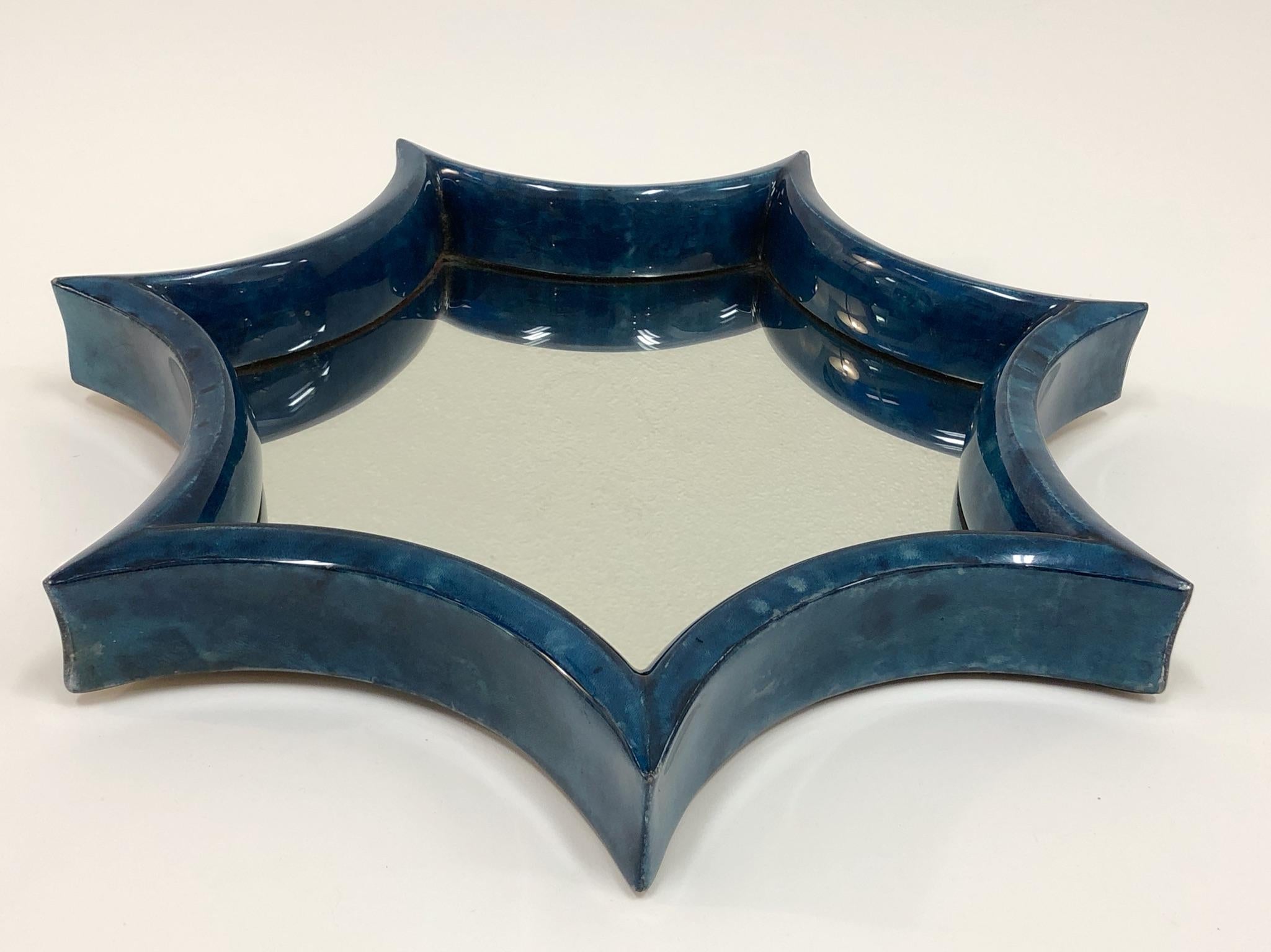 A beautiful 1980s star shape goatskin wall mirror. The frame is constructed of wood covered with blue stained goatskin and then cleared lacquered.
Dimensions: 20” diameter 2” deep.