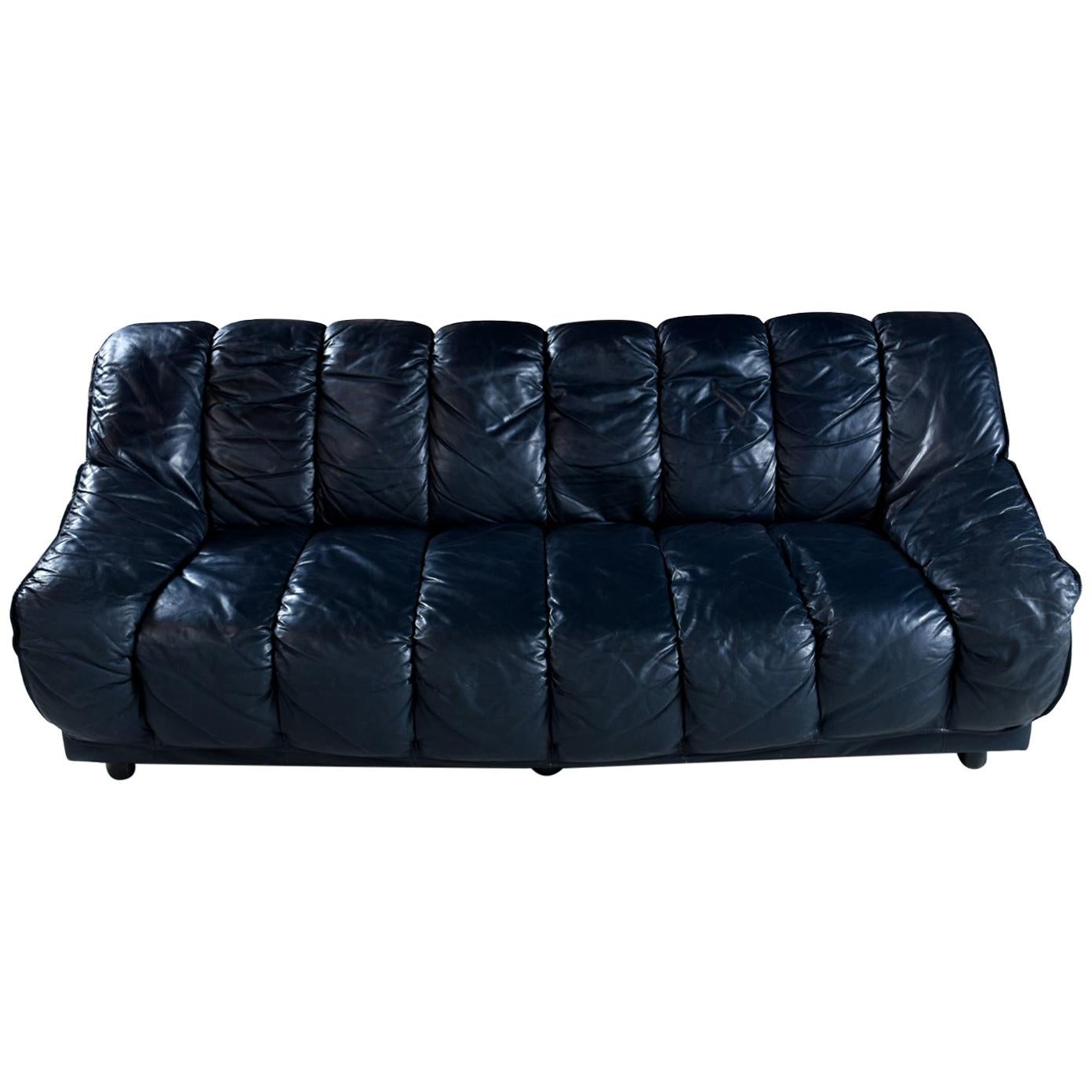 This luxurious Italian leather armchair challenges the eye. It does appear to be black, but in the right light one can notice that the leather is actually a deep blue color. The chair sits like a dream with the amply stuffed cushions cradling the