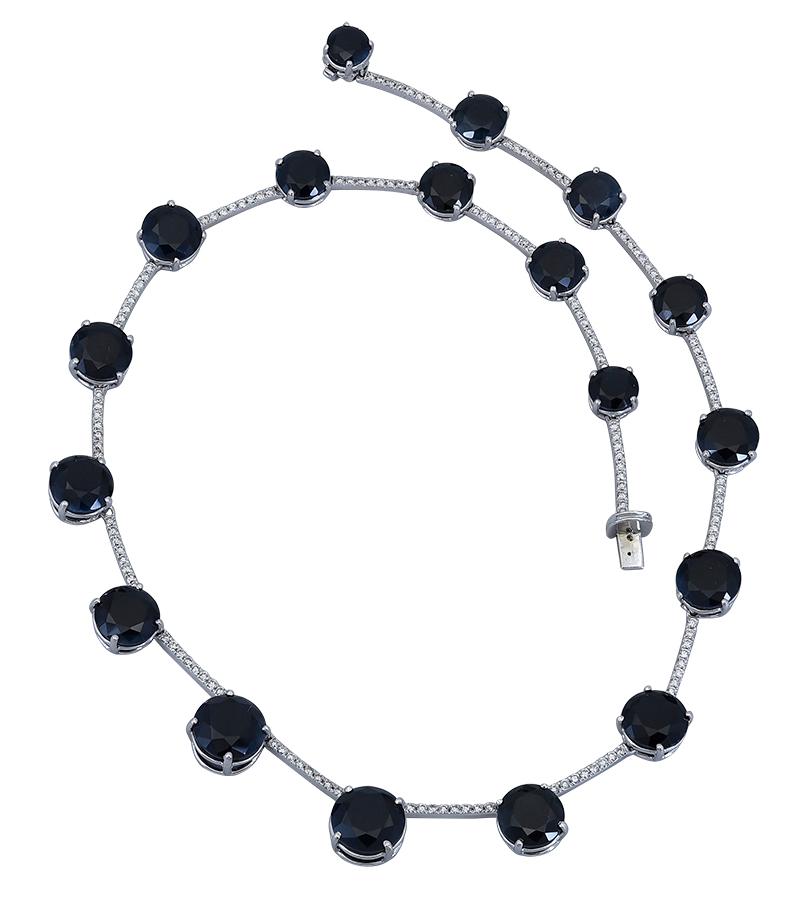 A unique piece of jewelry showcasing an intertwined rope chain set with equidistant dark blue sapphires. Made in white gold. 
16 inches in length.
0.29 inches max-width.
Sapphire: 18 round total carat weight approx. 45.09 cts. (1-3 cts. each
